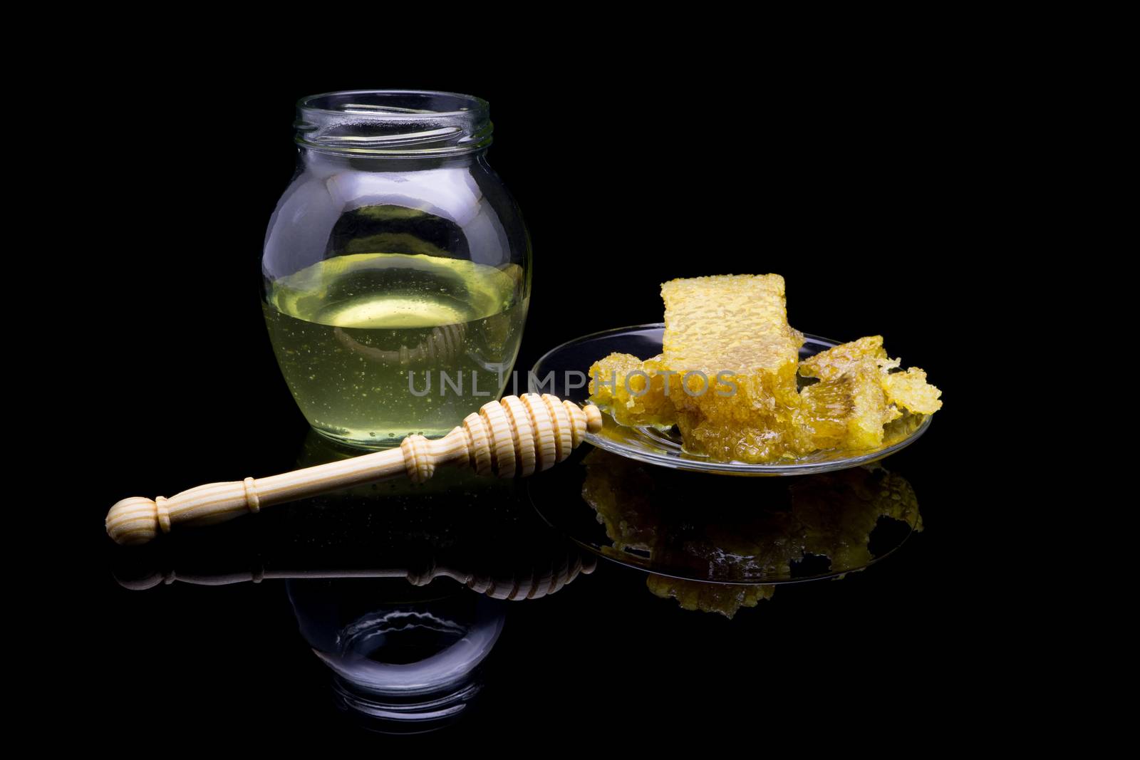 Honey with honeycombs on a glass plate on a black background