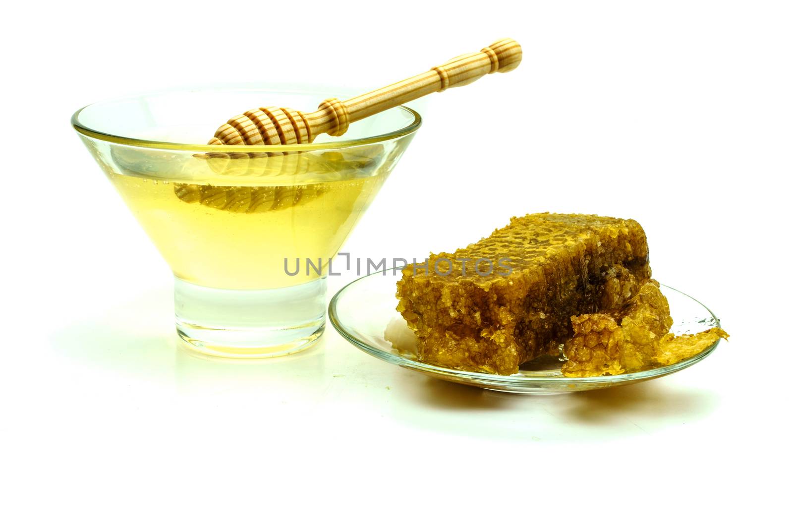 Honey with honeycombs on a glass plate on a white background
