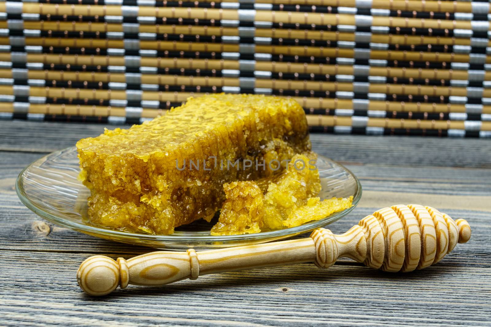 Honey with honeycomb in a glass plate on a wooden table