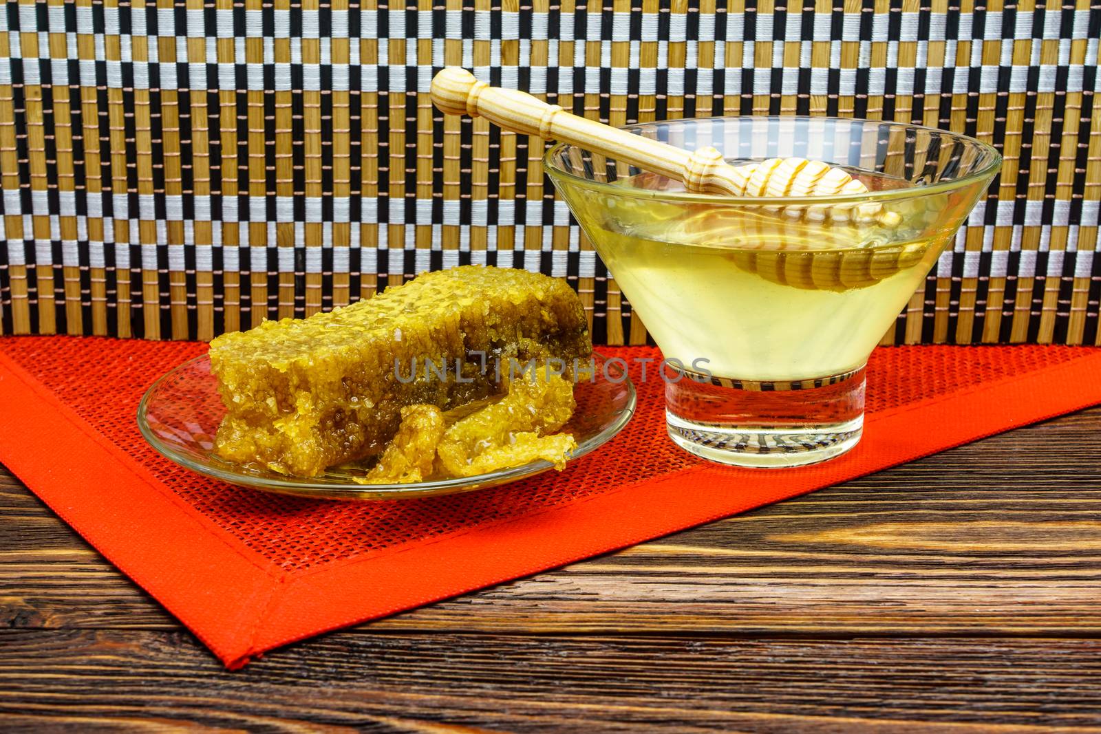 Honey with honeycomb in a glass plate on a wooden table