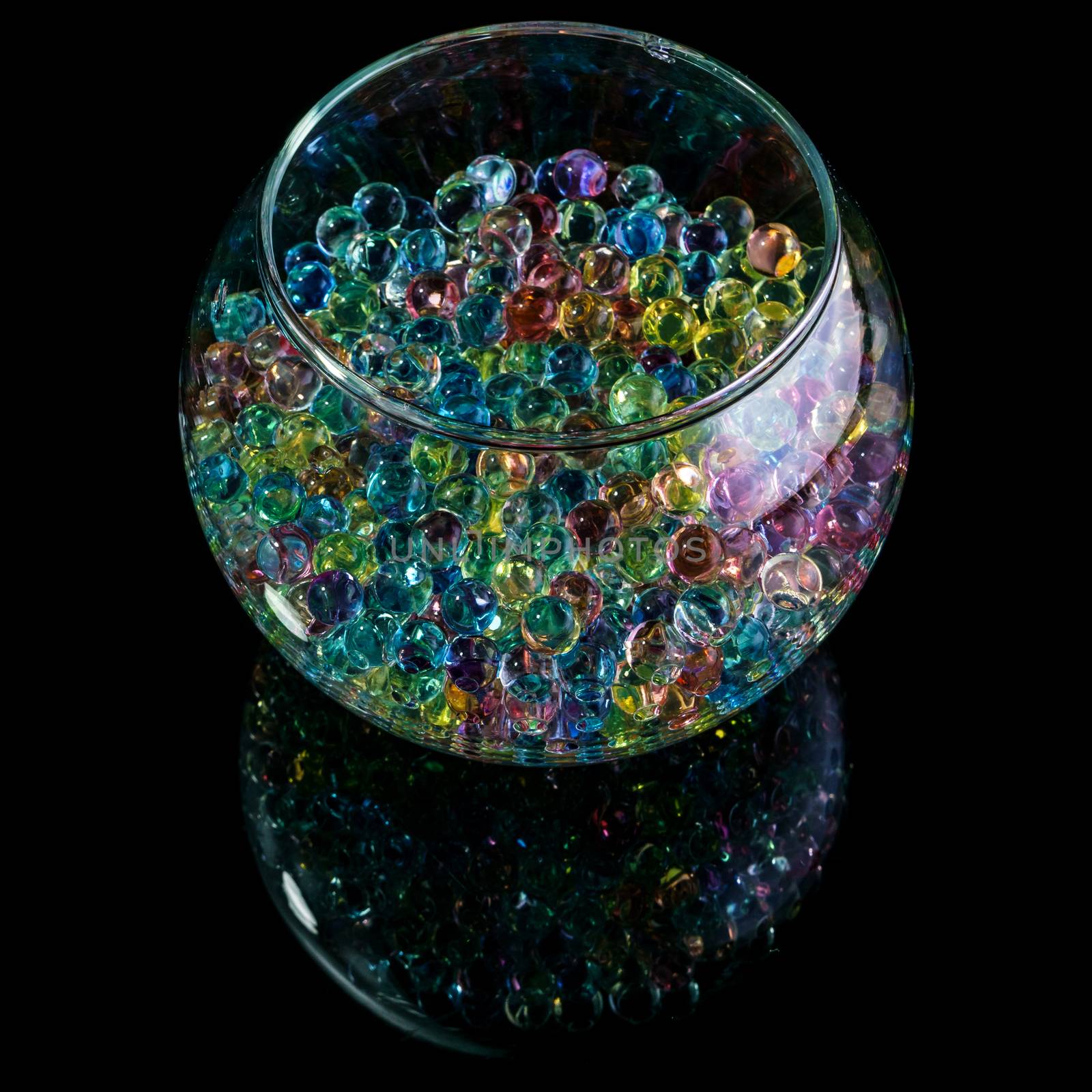 Colored hydrogel balls in a glass vase on a black background