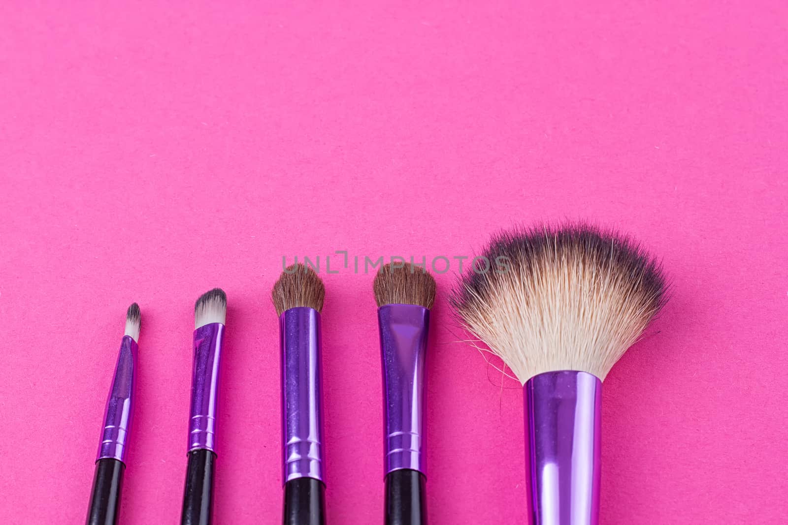 Set of makeup brushes on pink background. Top view point, flat lay.