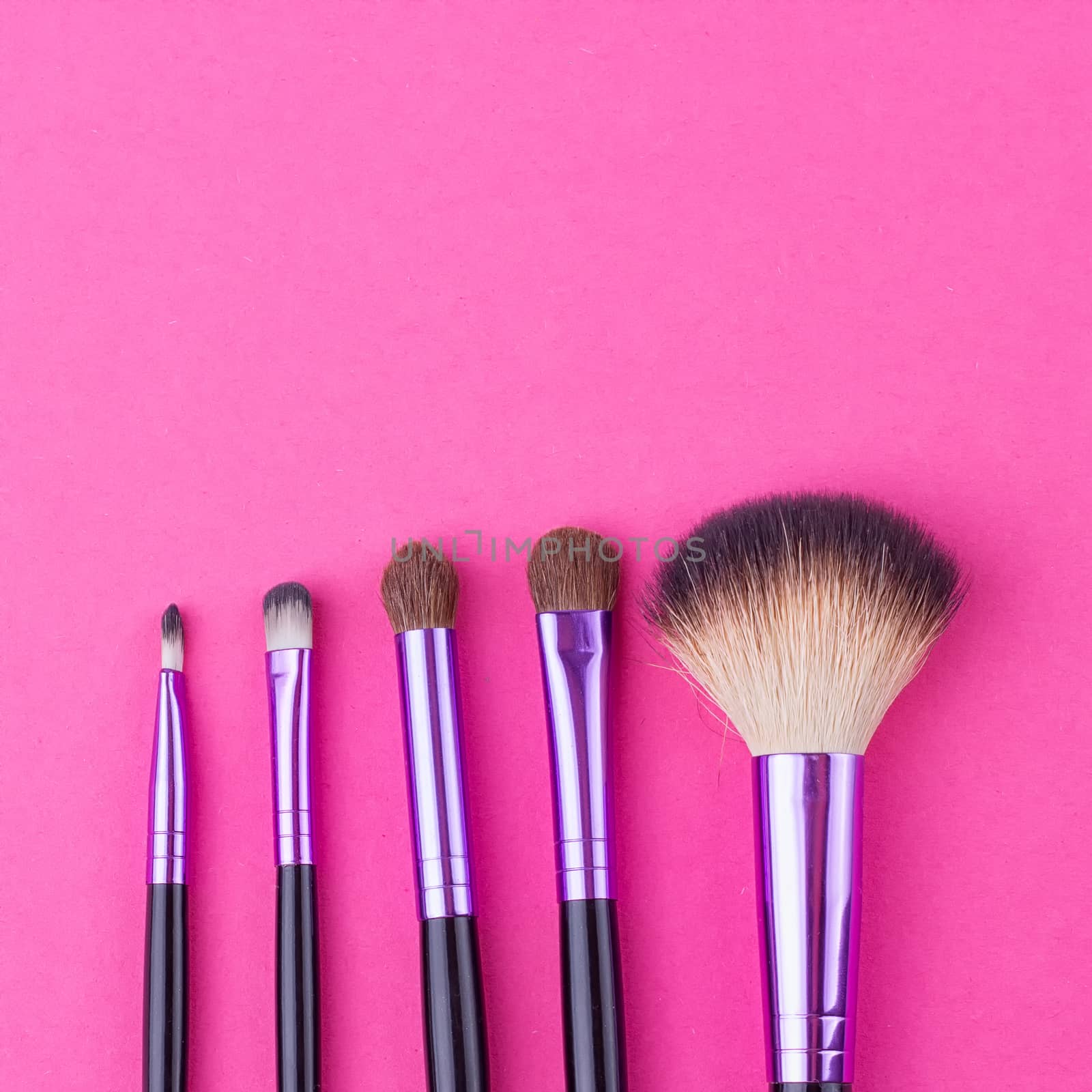 Set of makeup brushes on pink background. Top view point, flat lay.