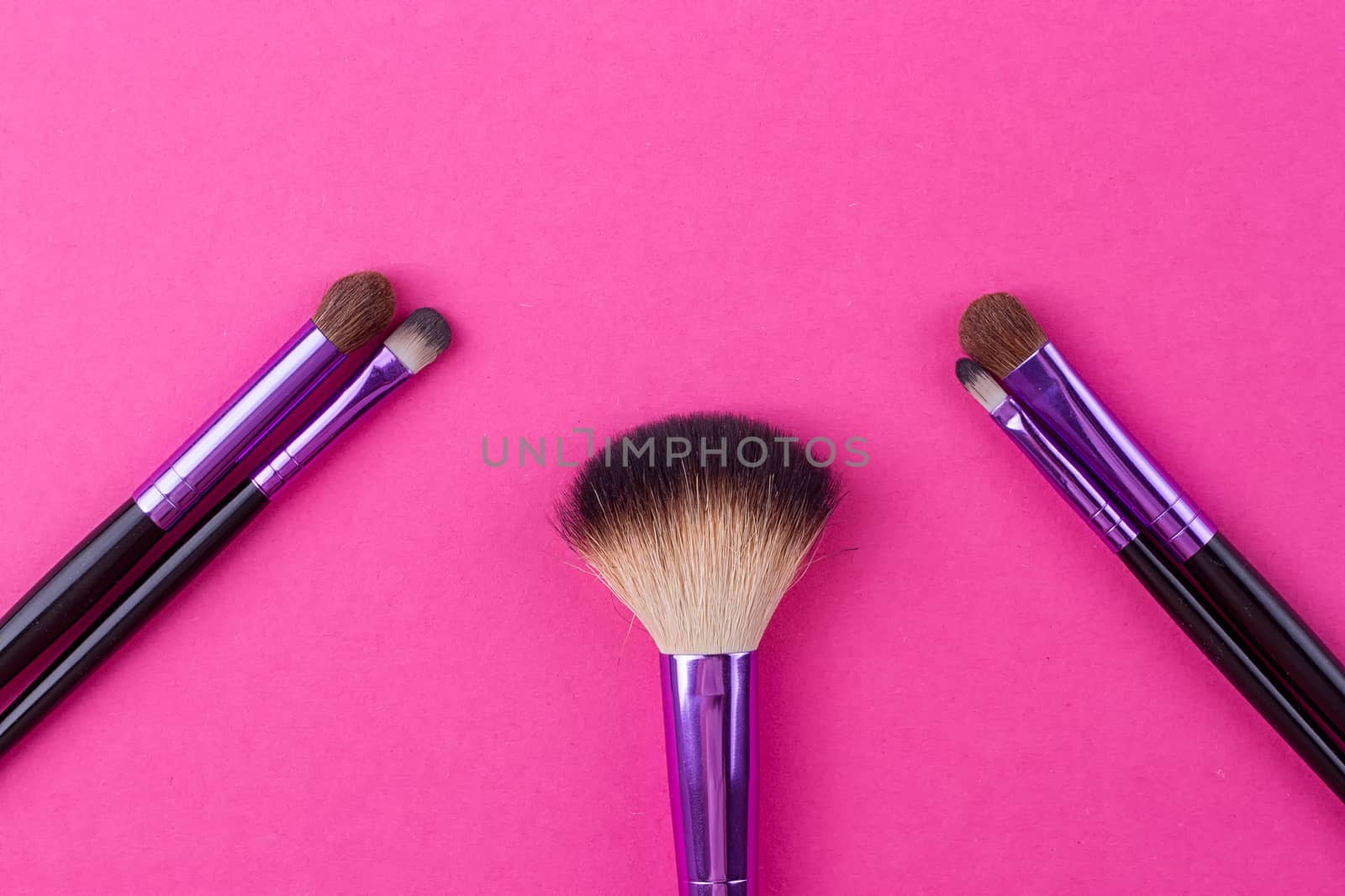 Set of makeup brushes on pink background. Top view point, flat lay.