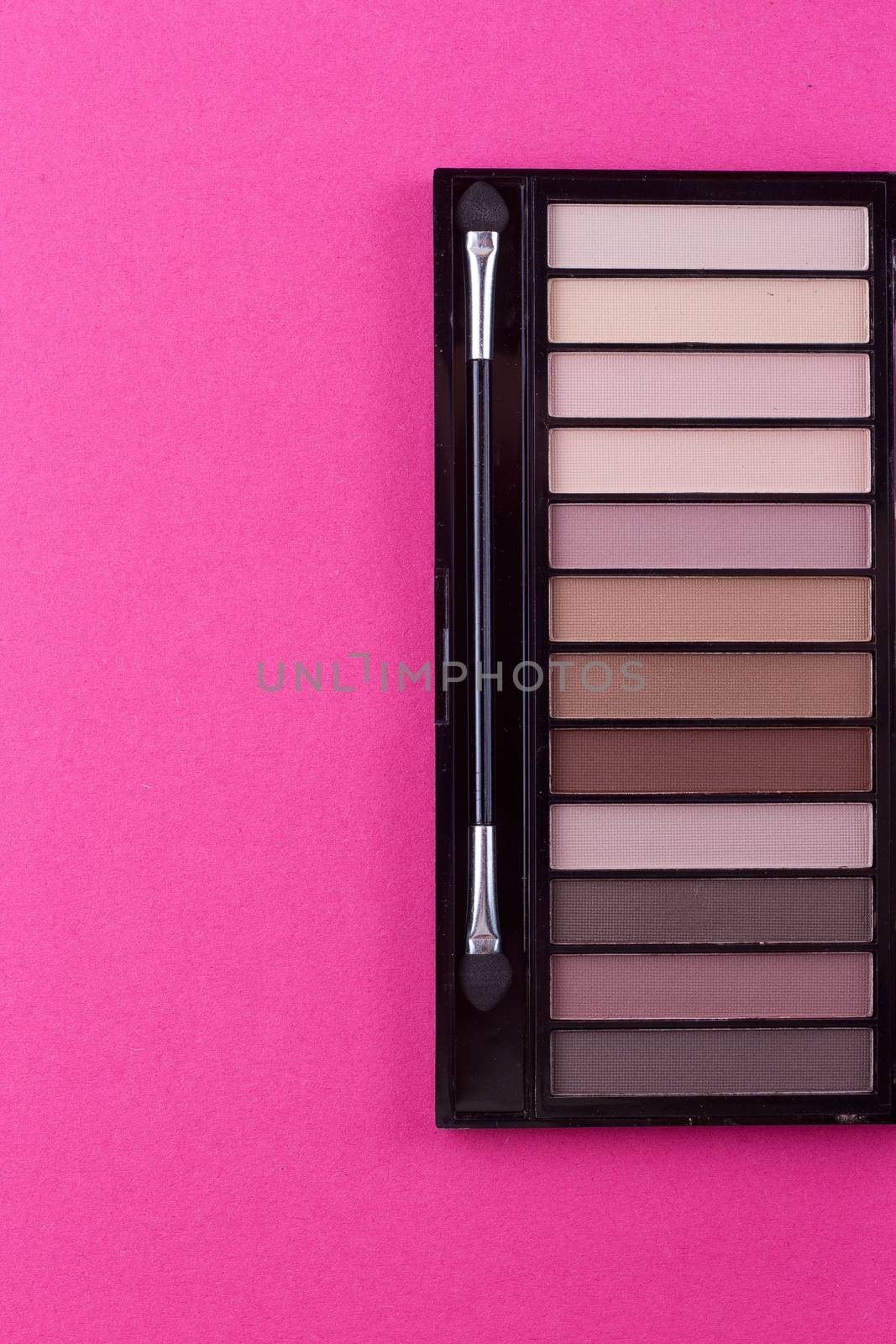 Set of nude eyeshadows in black case on pink background