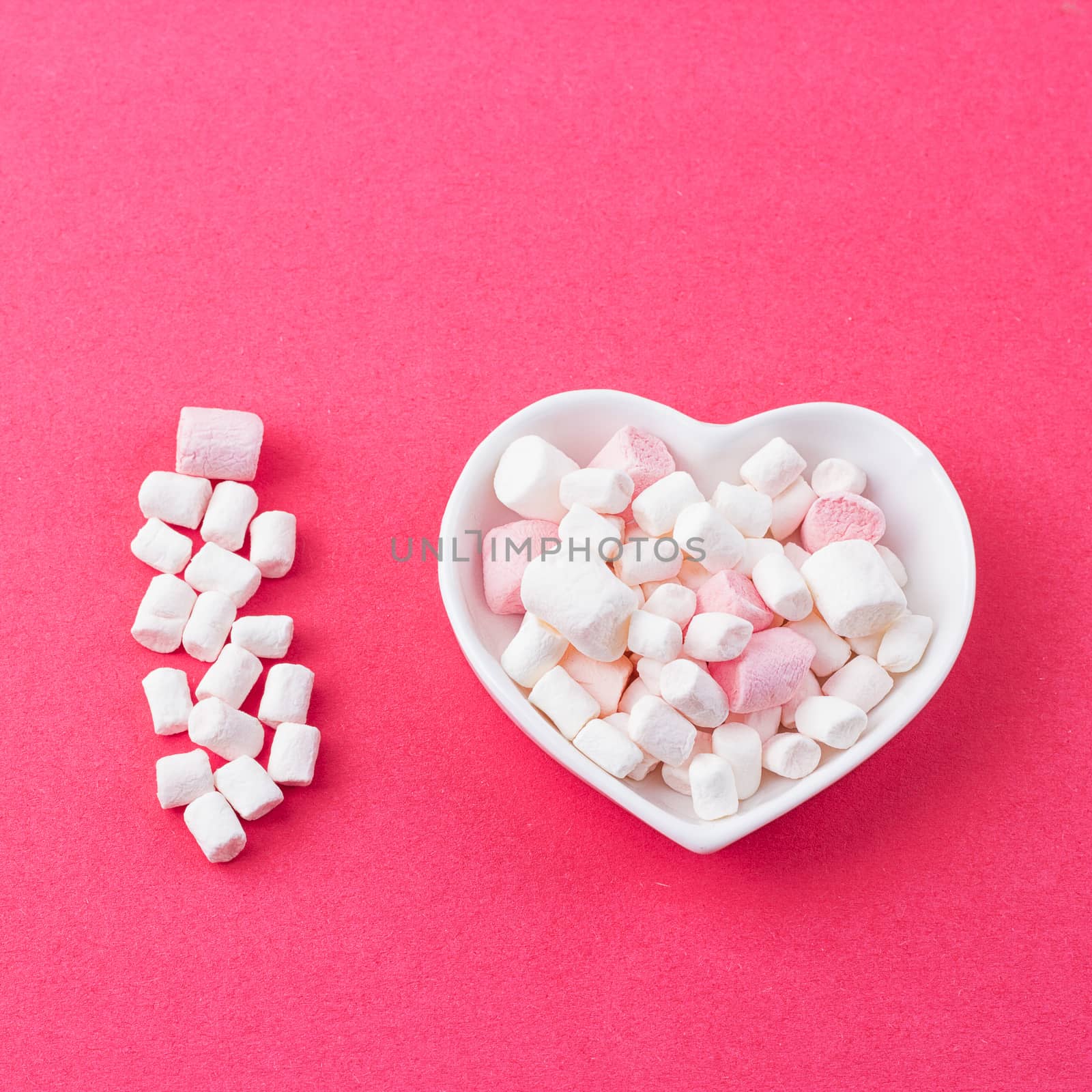 Love concept. Plate in the shape of heart with a marshmallow on a pink background. I love