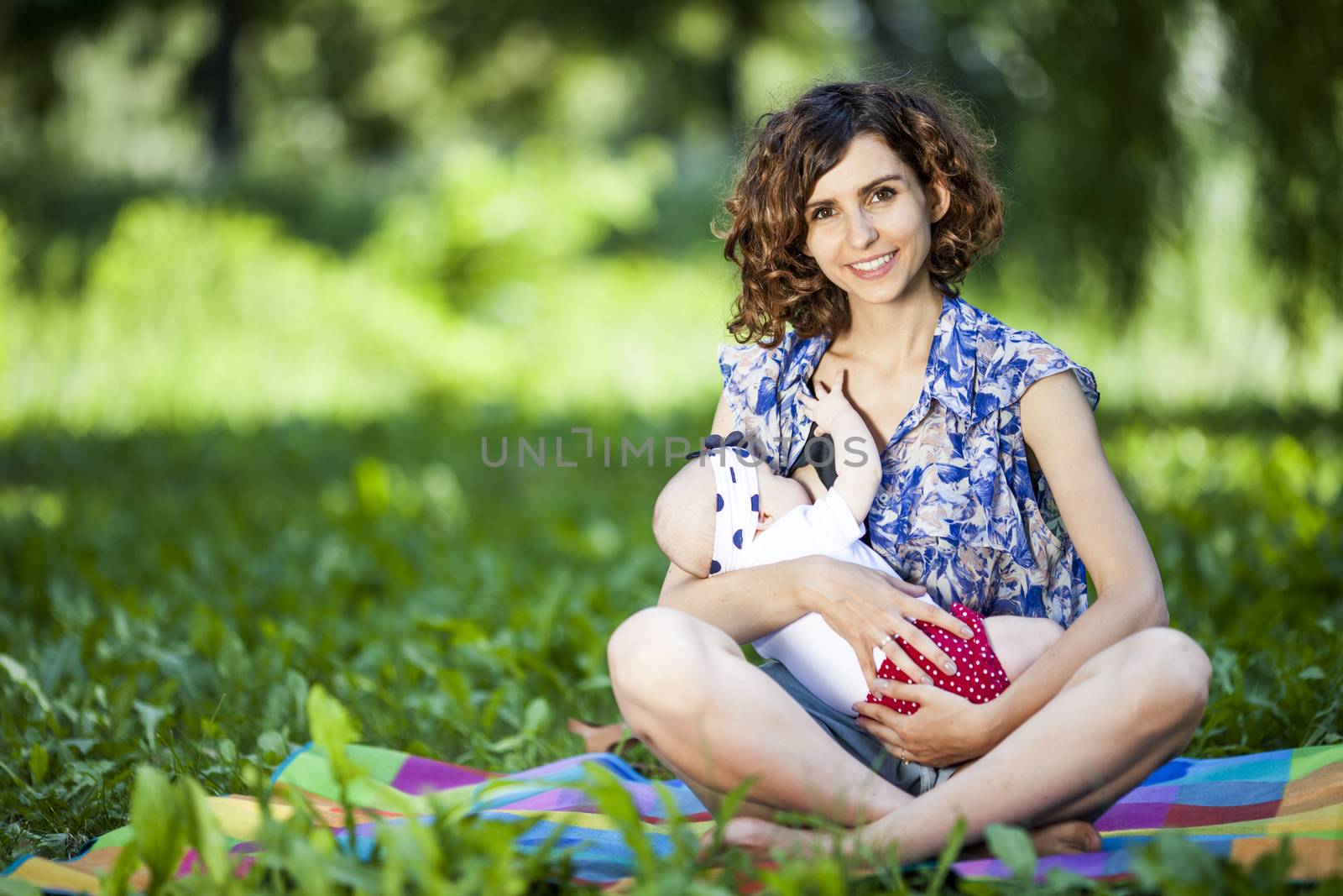 Young beautiful mother sits on blanket with her daughter during a picnic in the park