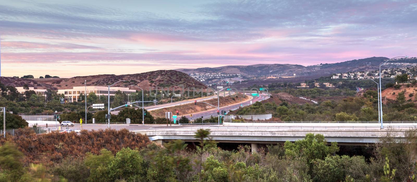 Highway in Irvine, California, at sunset with mountain range in the distance in summer