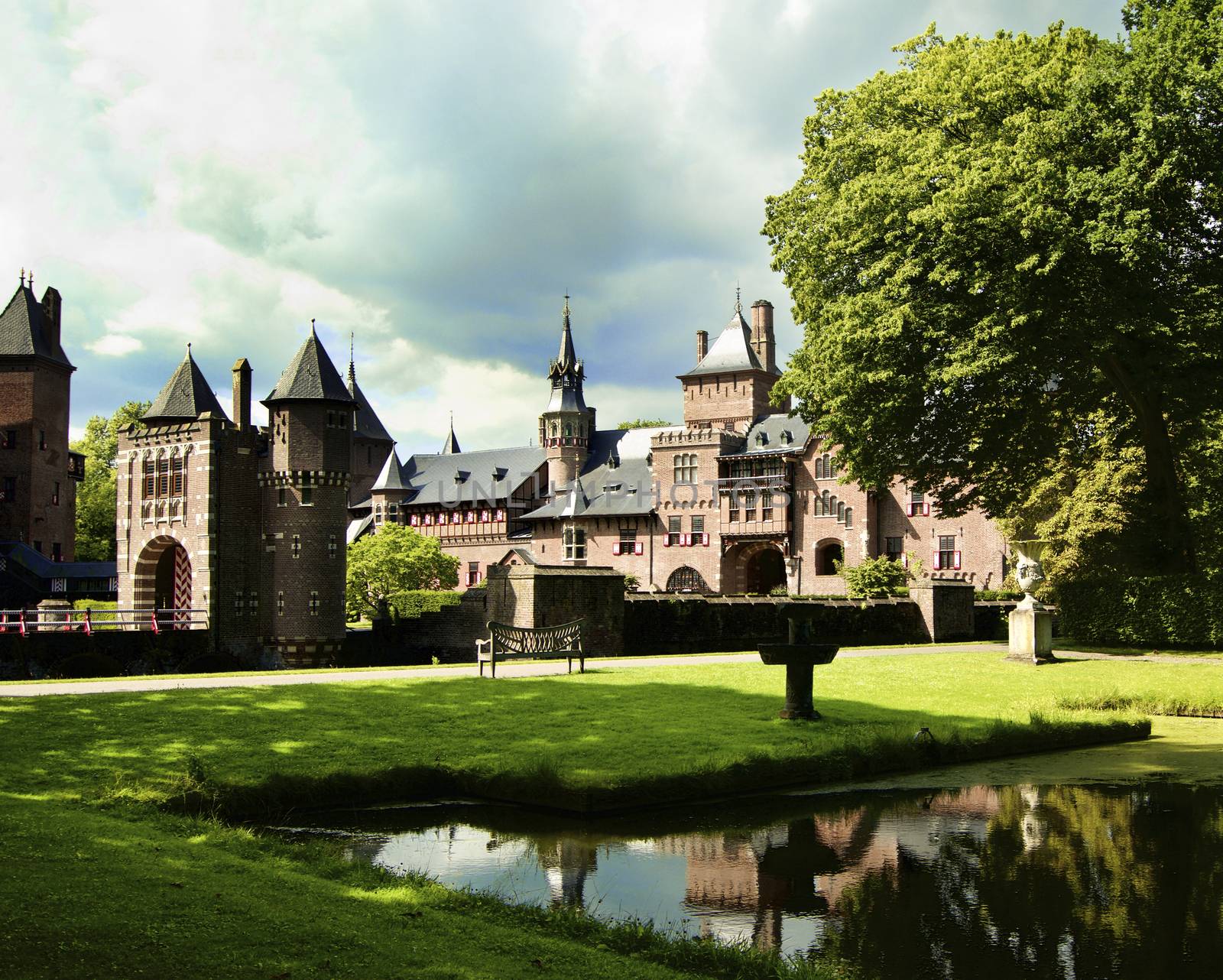 Medieval Castle De Haar from side of Back Yard with Reflection on Pond against Cloudy Sky Outdoors. Utrecht, Netherlands