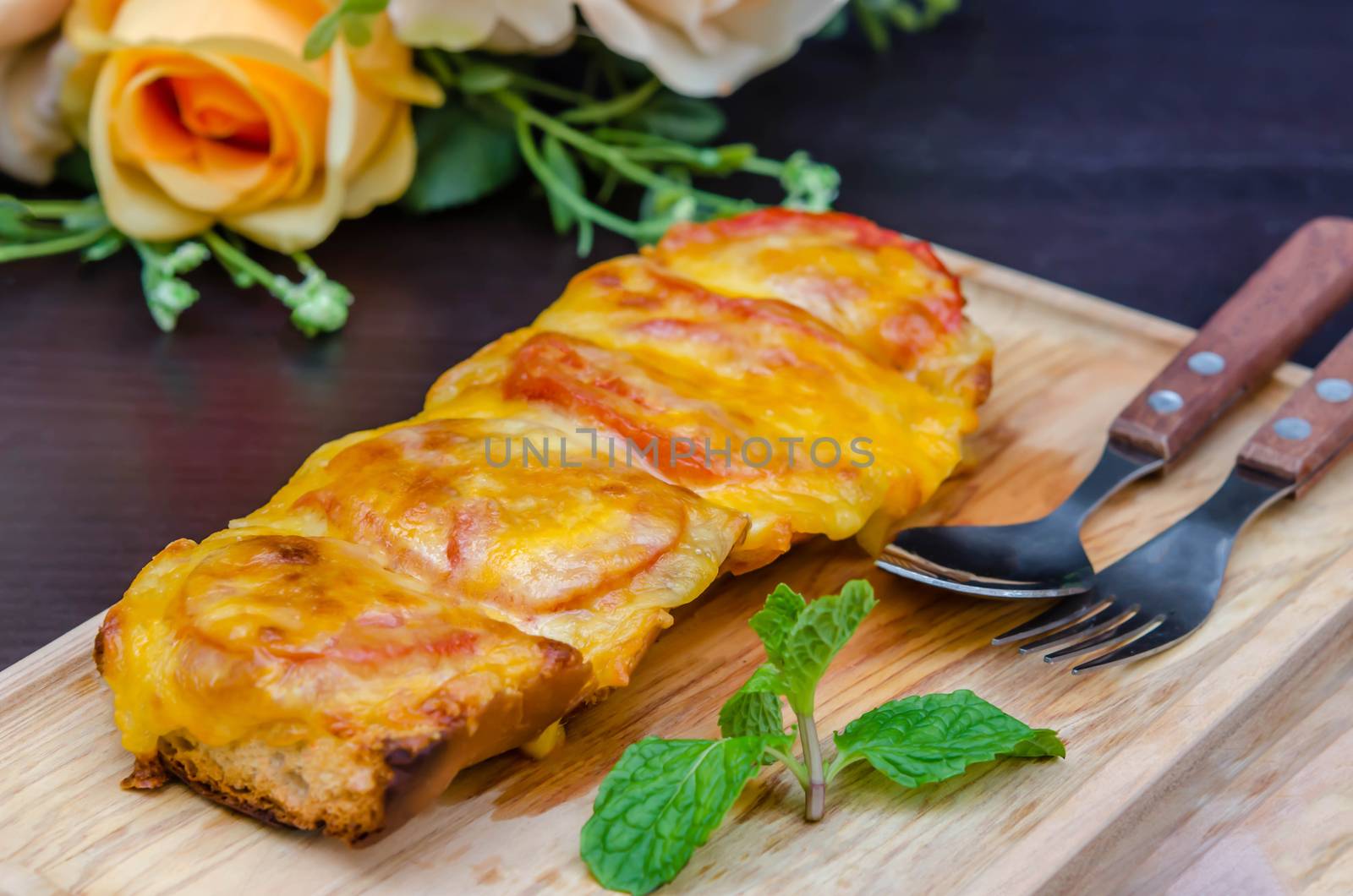 homemade French bread roll, topped with fresh tomatoes, melted cheddar, Mozzarella and Parmesan