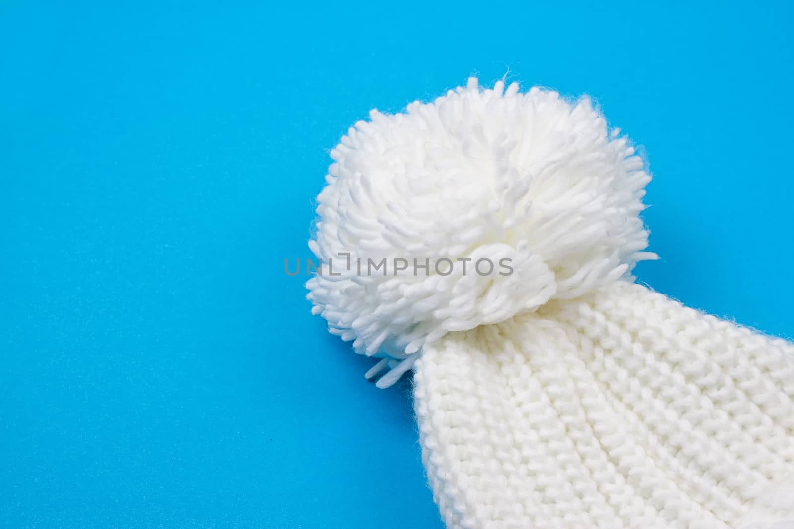 White winter knitted cap on blue background