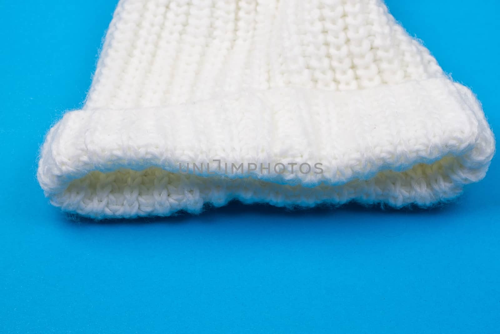 White winter knitted cap on blue background