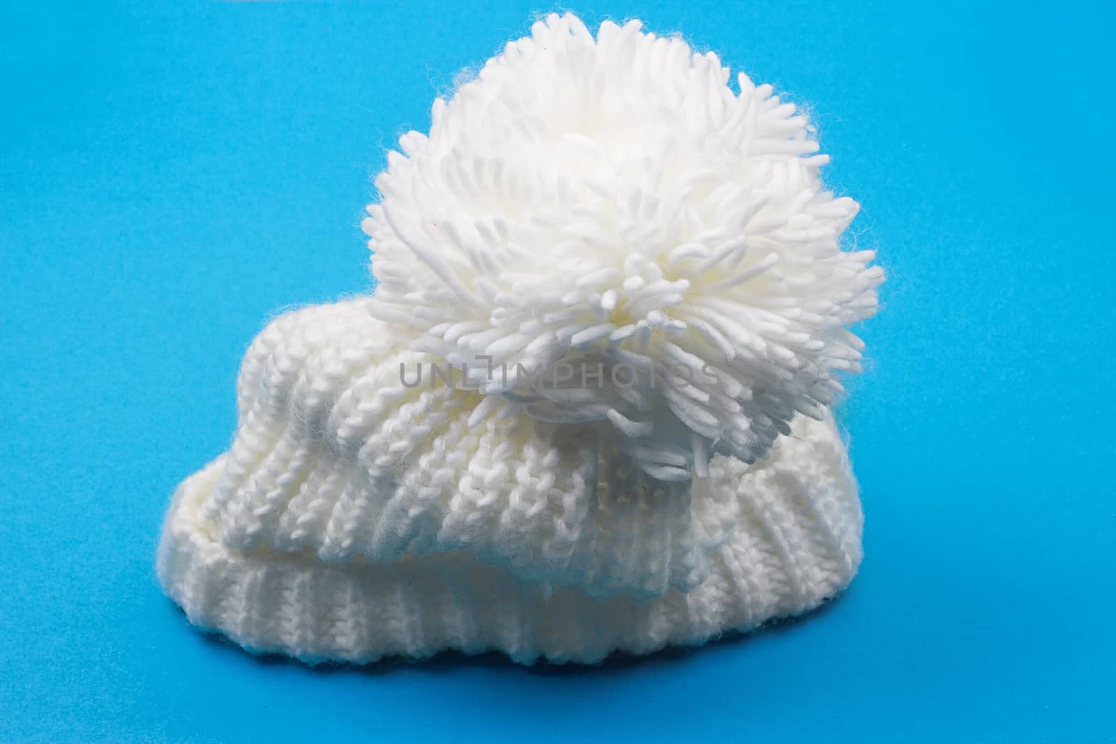 White winter knitted cap on blue background