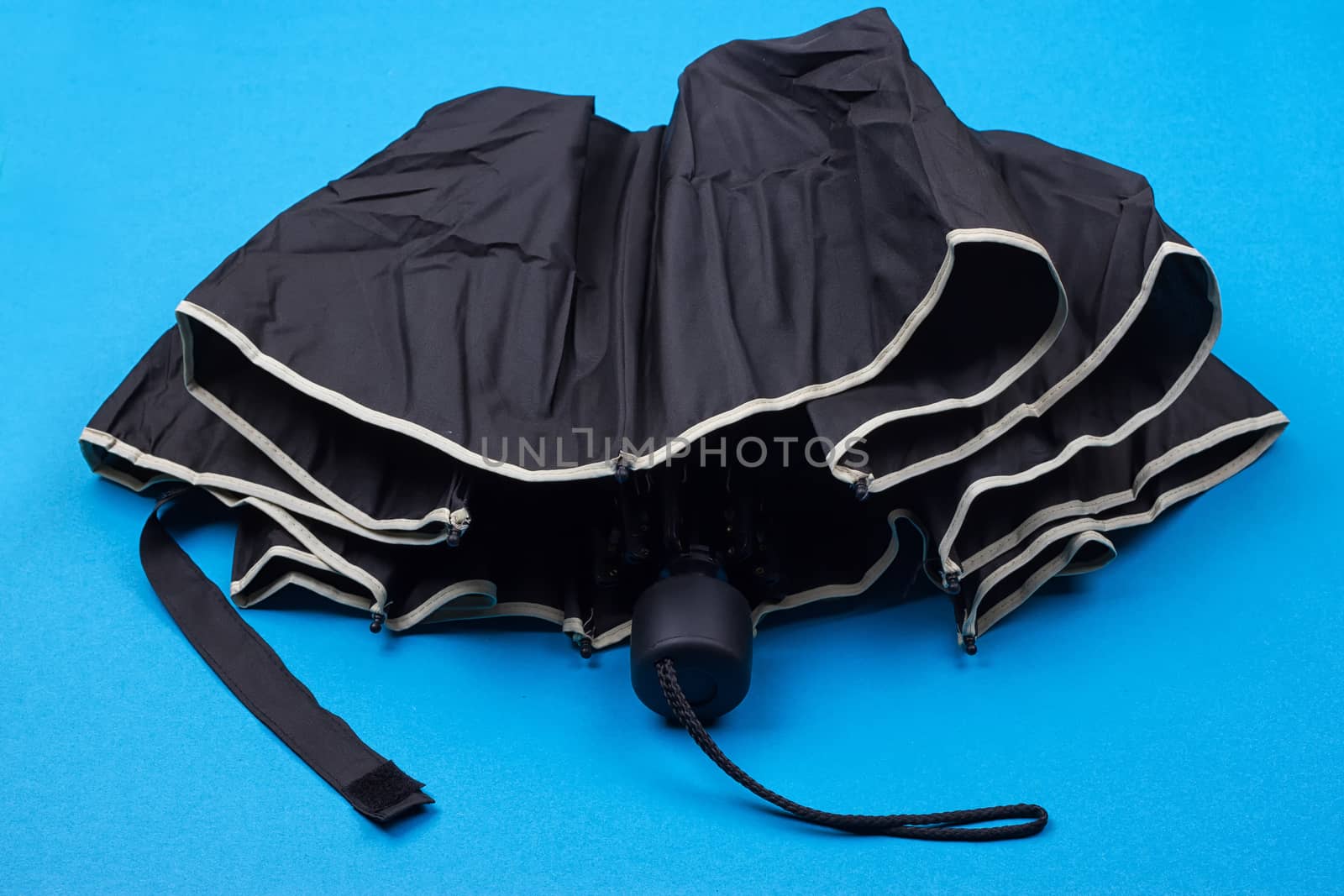 closed black umbrella on the blue background