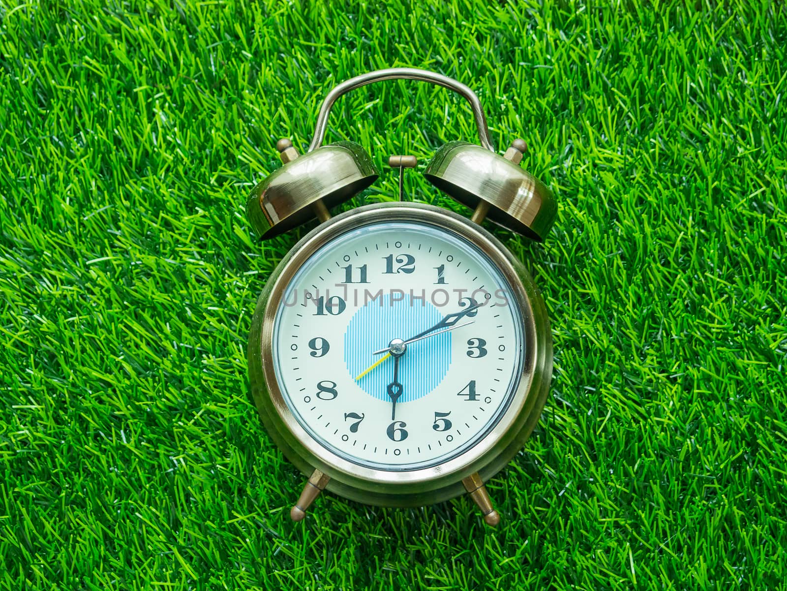 Alarm clock on green lawn by supirak