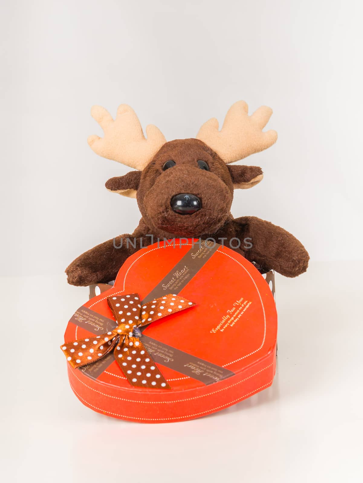 Deer doll and heart-shaped gift box on white background. by supirak
