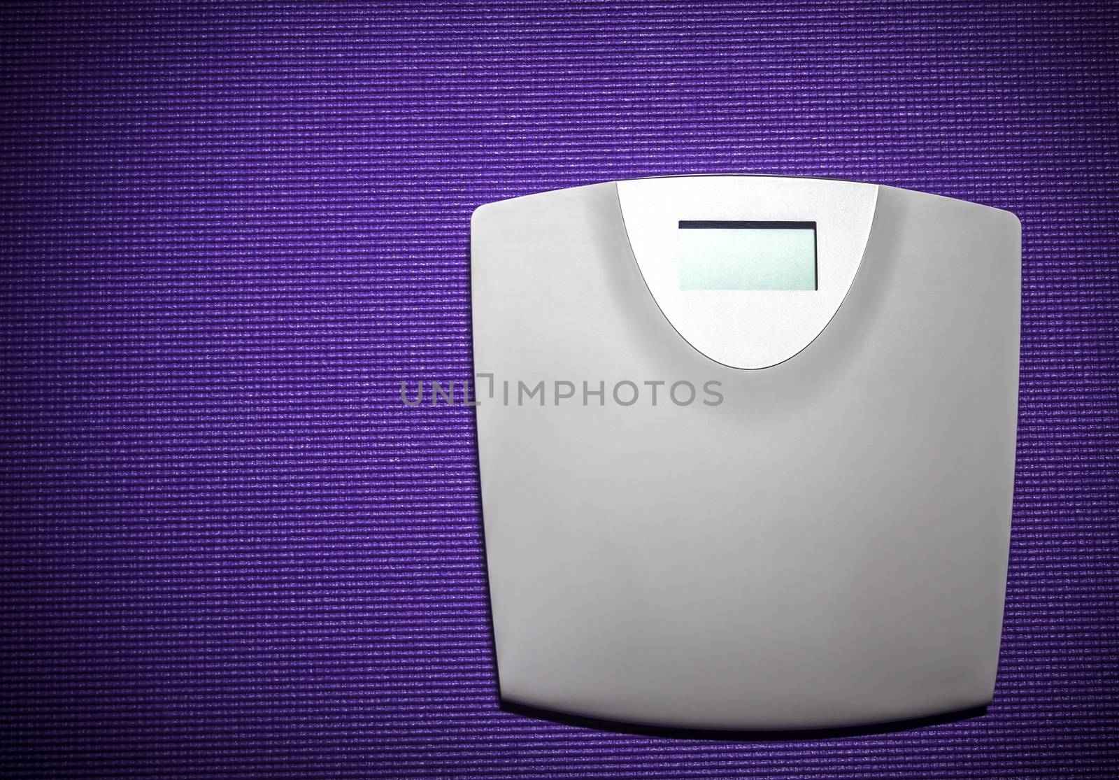 Digital weight scale on purple carpet background