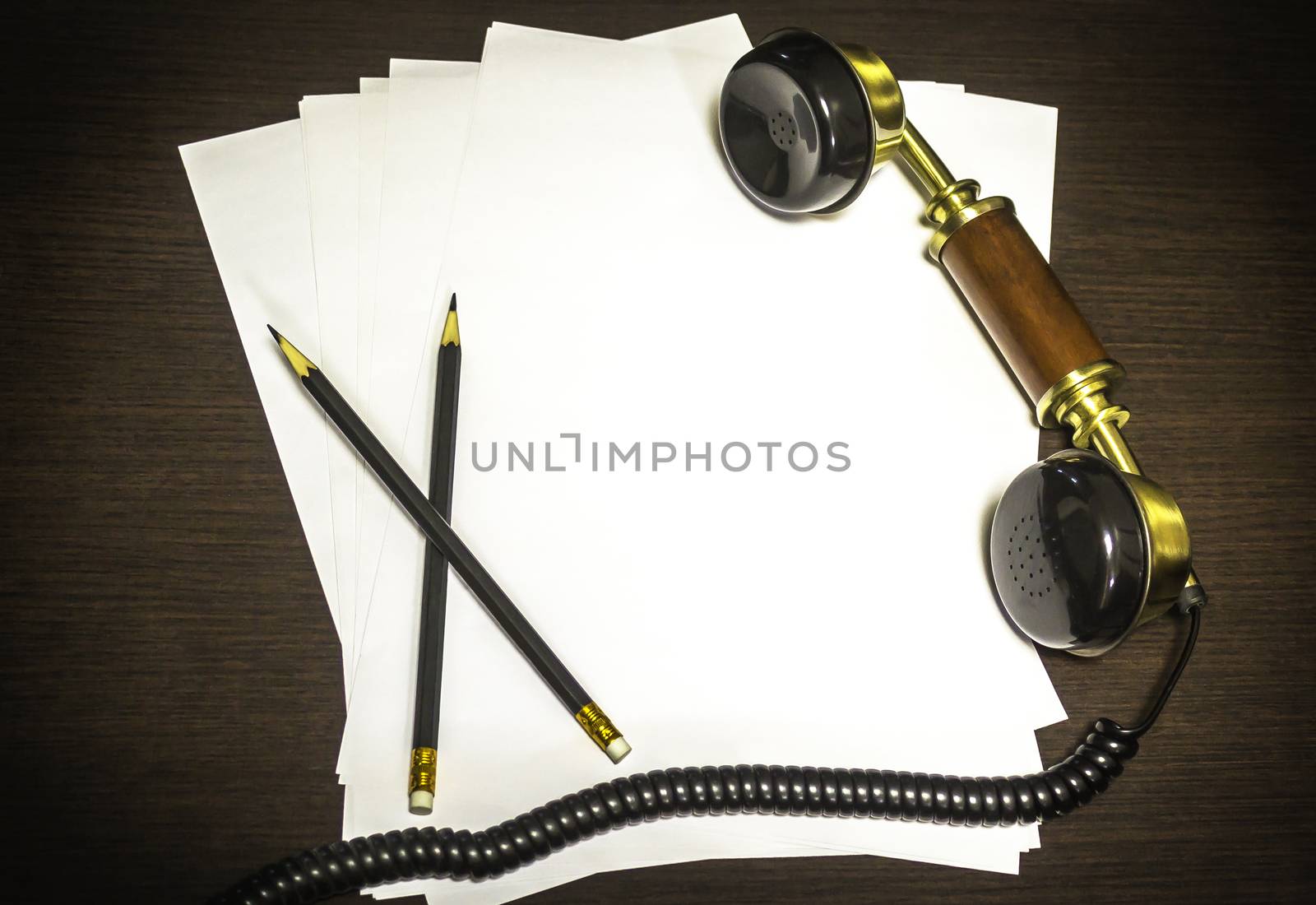 Vintage earphone on wooden background with empty paper and two pencil