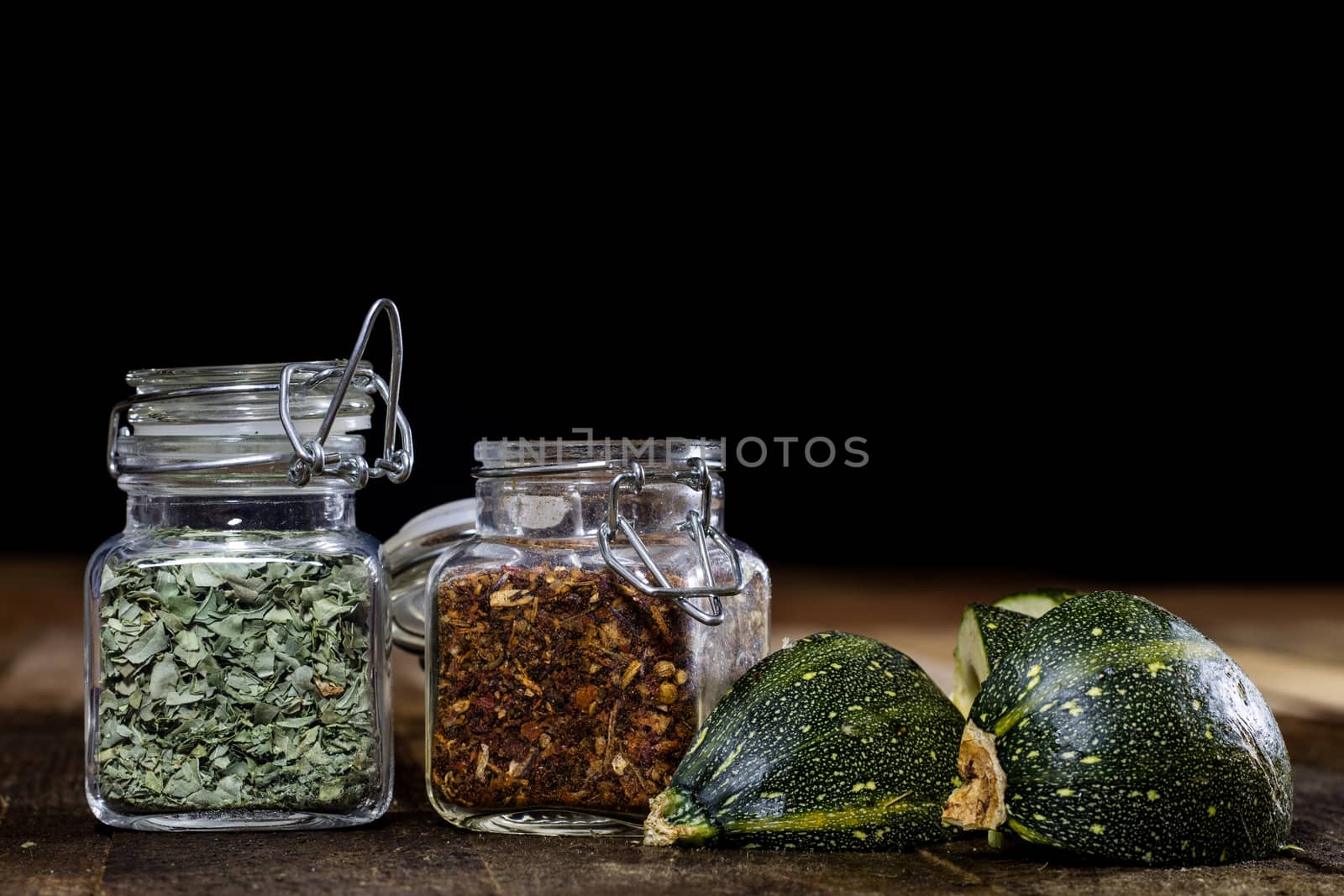 Tasty pumpkin and spices on a wooden kitchen table, black background