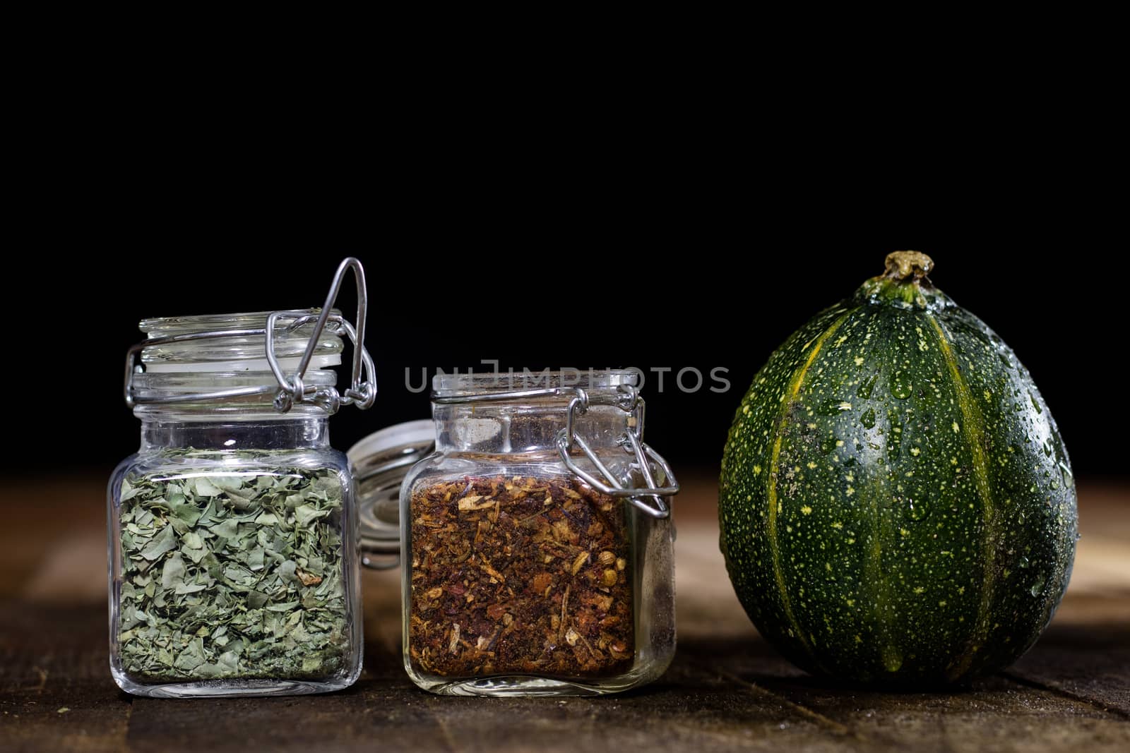 Tasty pumpkin and spices on a wooden kitchen table, black background