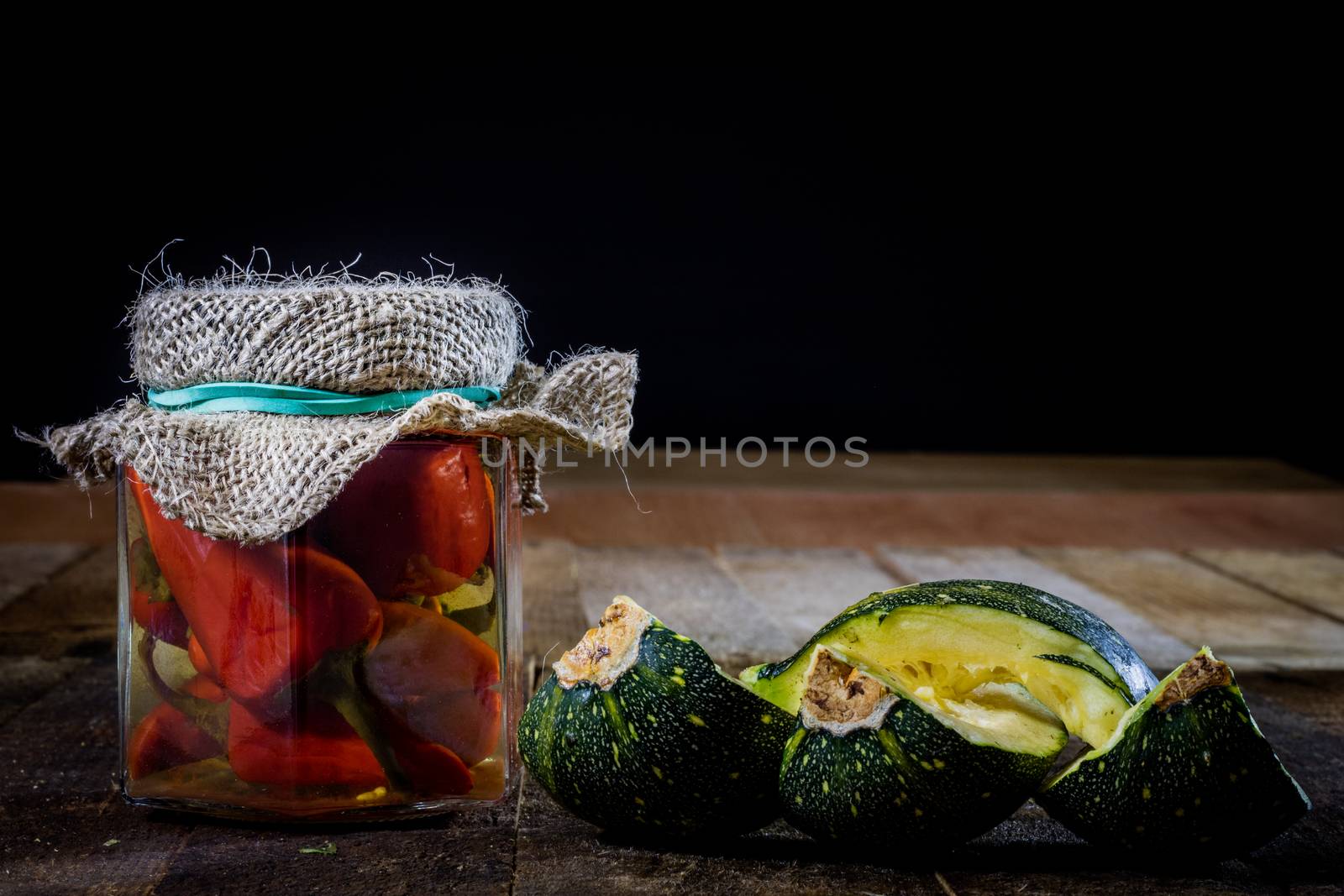 Pumpkin jars and spices. Preparations from your own garden. Wooden kitchen table. Black background.