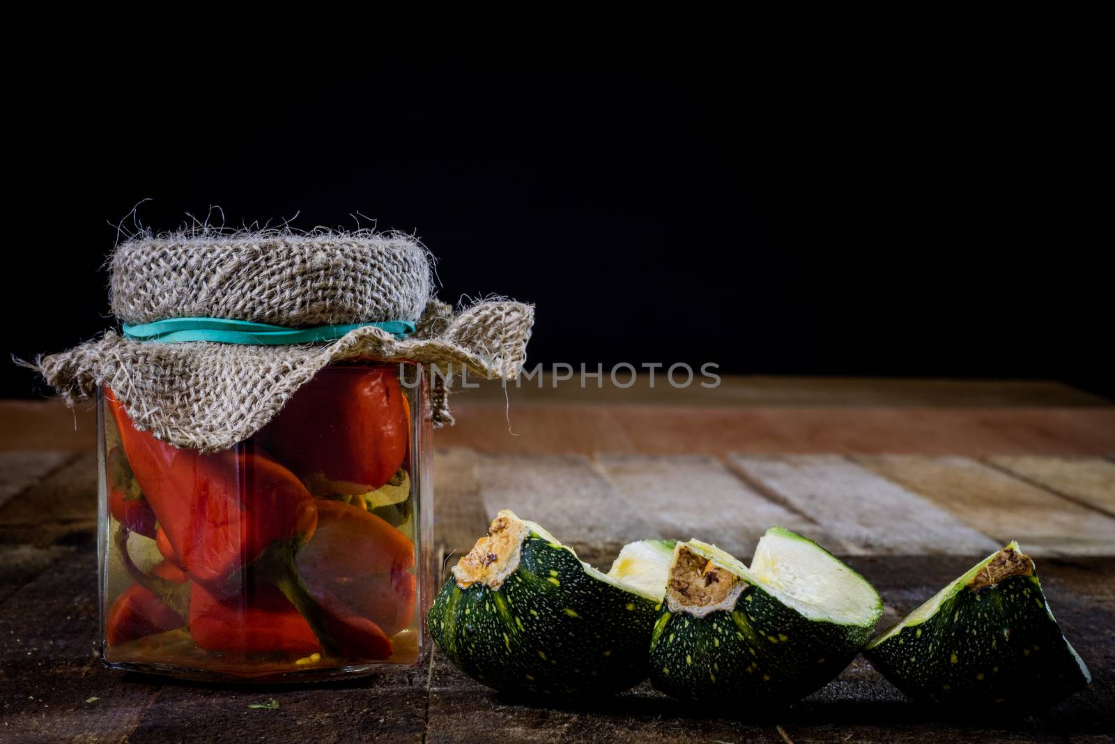 Pumpkin jars and spices. Preparations from your own garden. Wooden kitchen table. Black background.