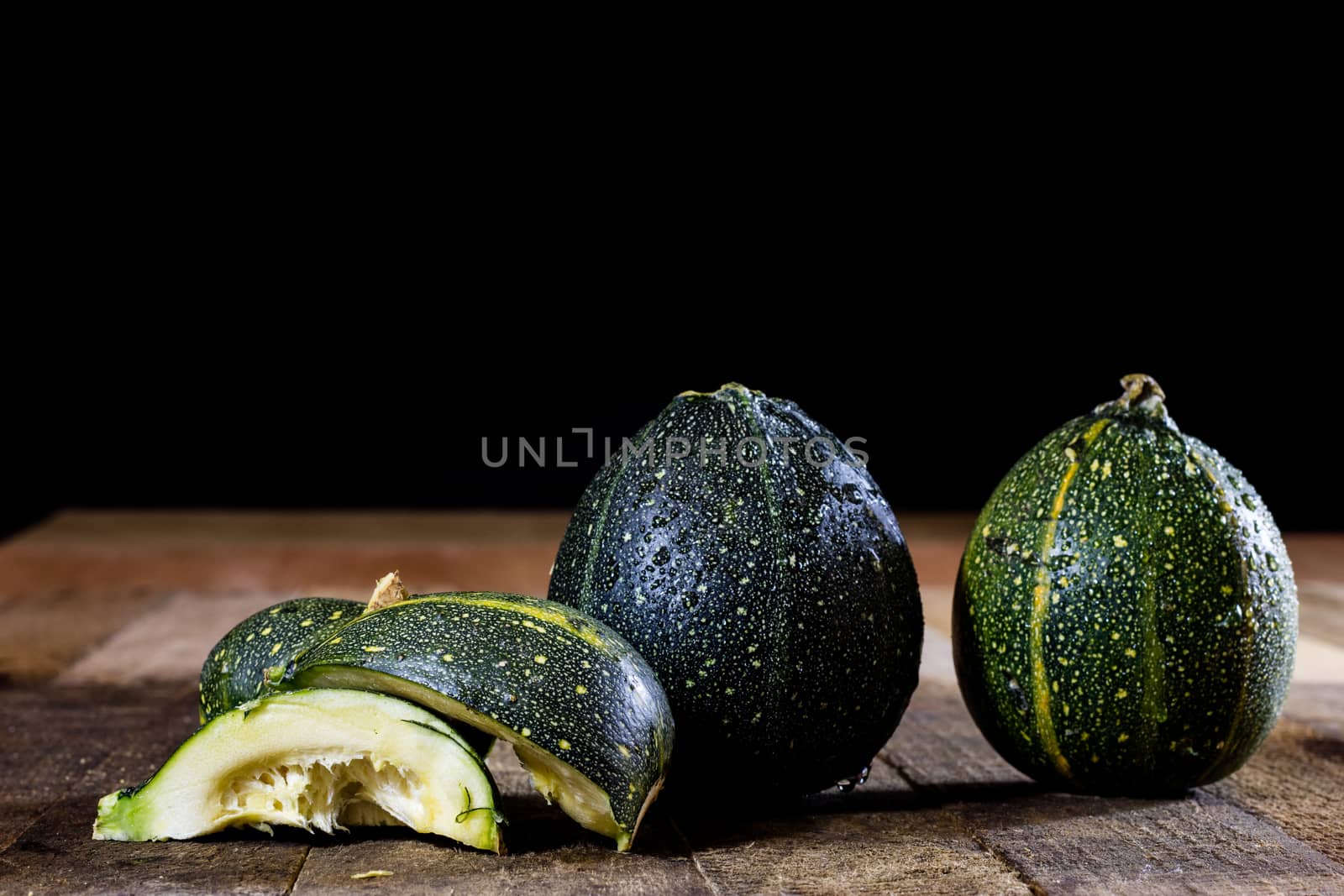 Tasty mini pumpkin on a wooden table, black background