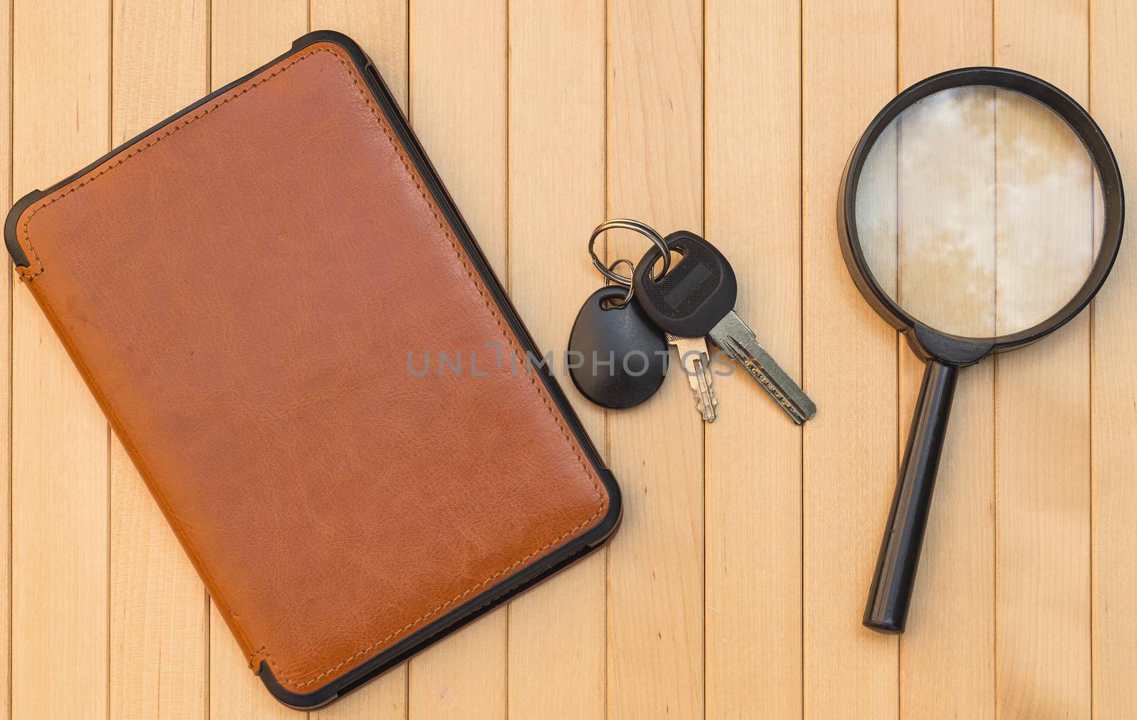 Magnifying glass e-book and keys on wooden background