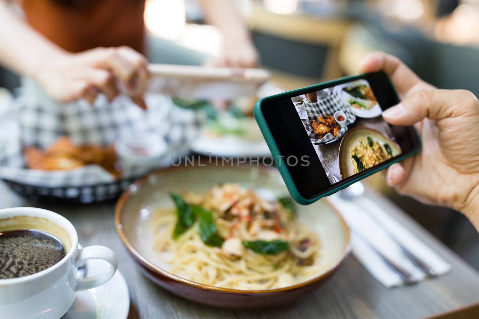 Friends taking photo on dish in restaurant by leungchopan