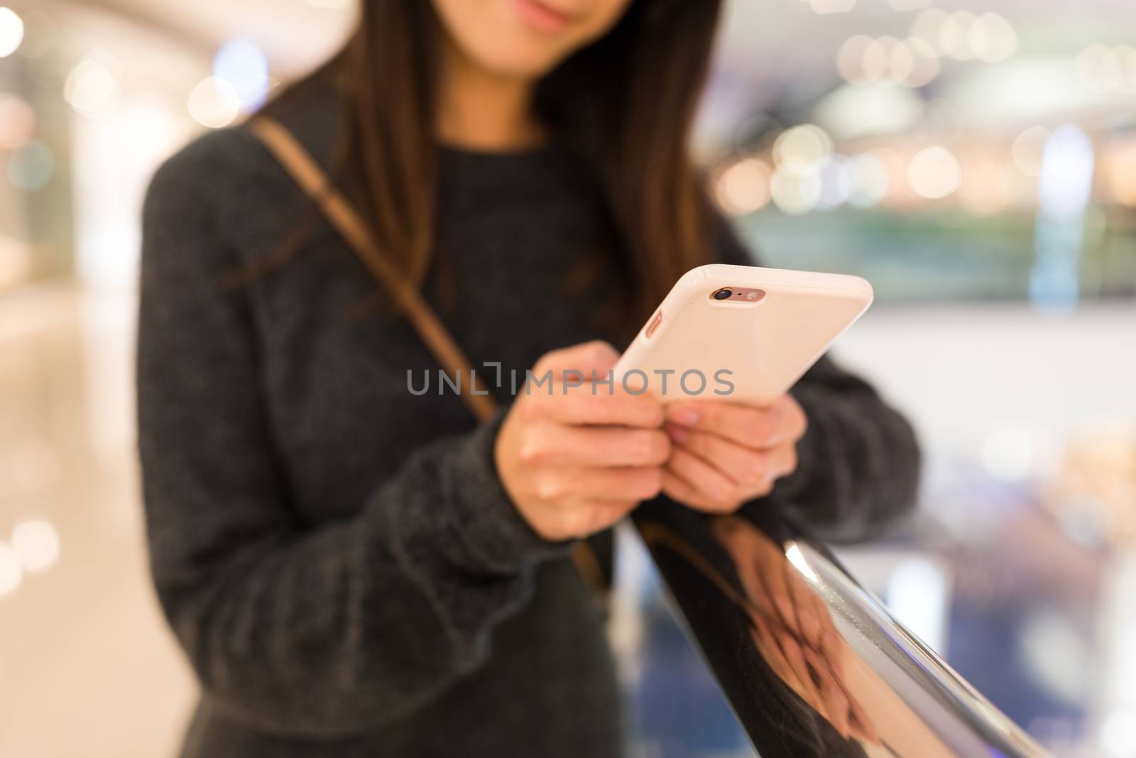 Woman working on cellphone in shopping mall by leungchopan