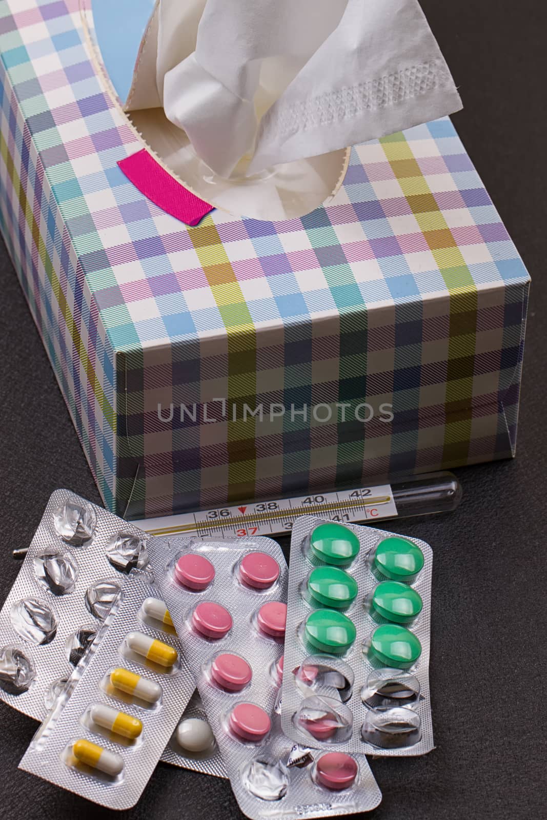 pills, thermometer, paper napkin and crumpled napkin on it. Top view, medicine concept photo. Black background