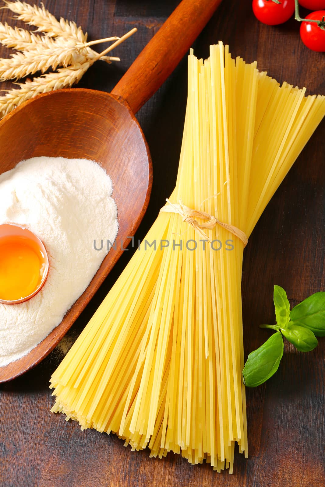 Bundle of dried spaghetti, scoop of flour and fresh egg