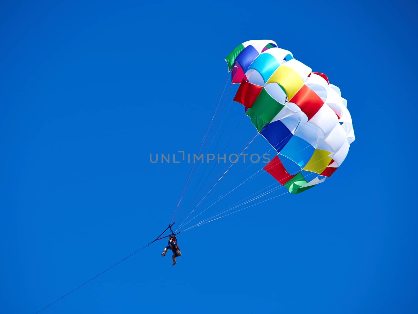 Parasailing with colorful parachute in clear blue sky popular vacation activity in summer resorts 