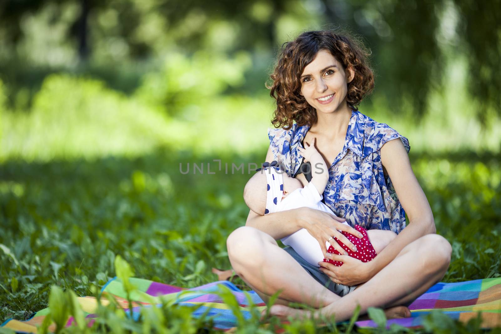 Young mother breast feeding a baby in the park by fikmik