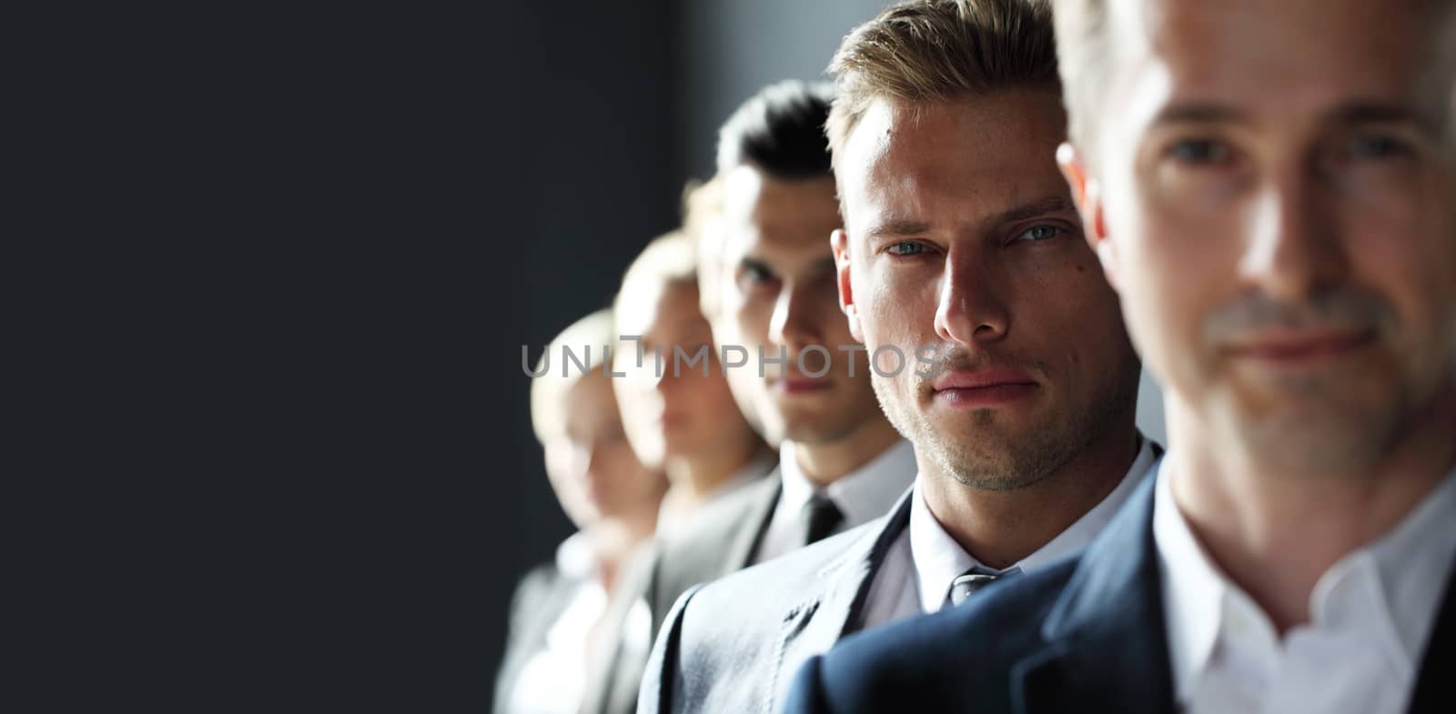 Serious business team standing in a row at office, gray copy space