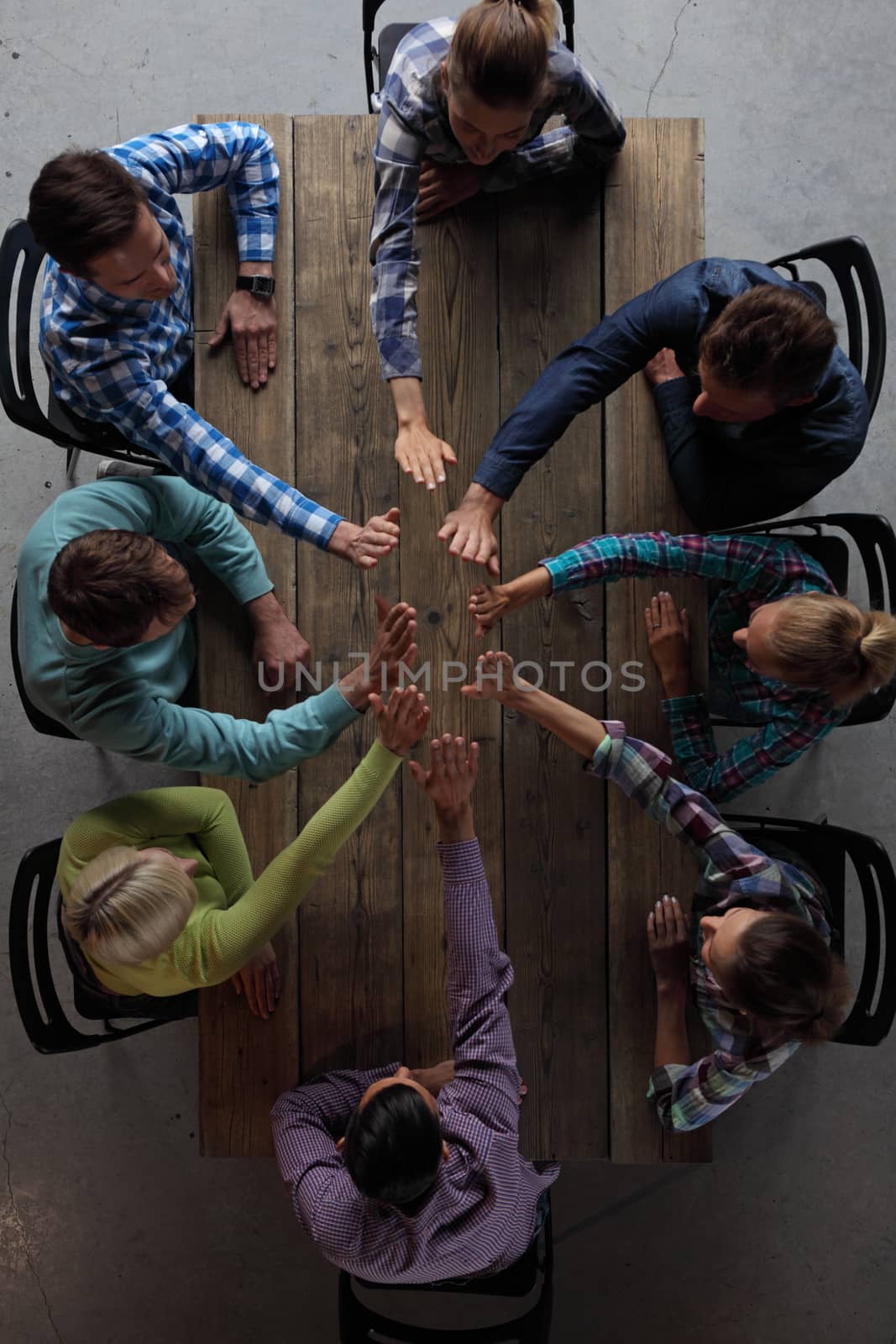 People sitting around table giving high five by ALotOfPeople