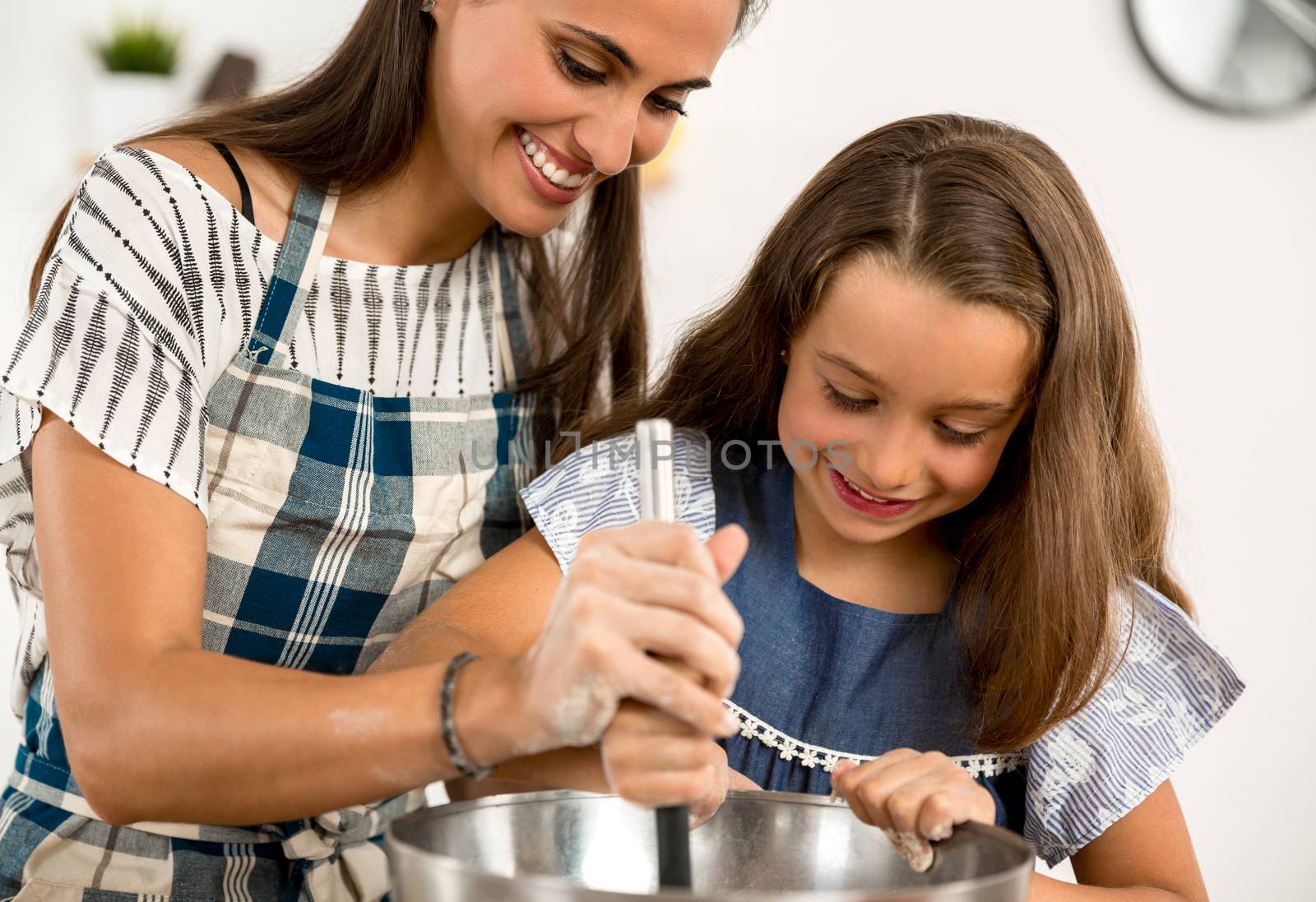 Shot of a mother and daughter having fun in the kitchen and learning to make a cake