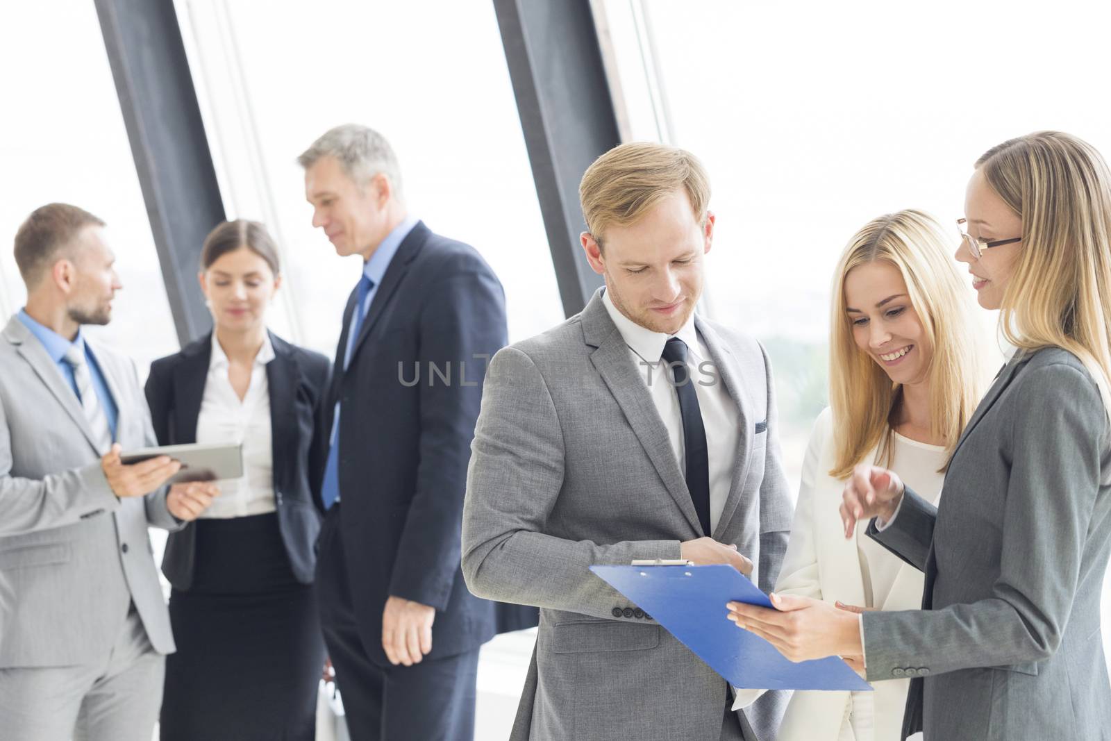 Confident business team talking in office against the window