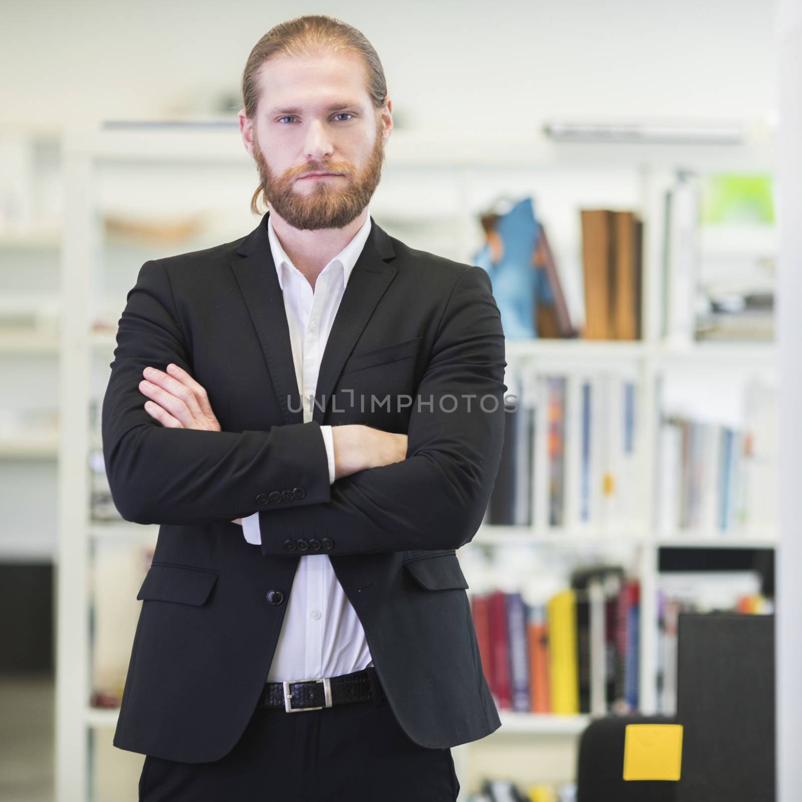 Portrait of hansome redhead bearded business man in office keeping arms crossed and looking at camera