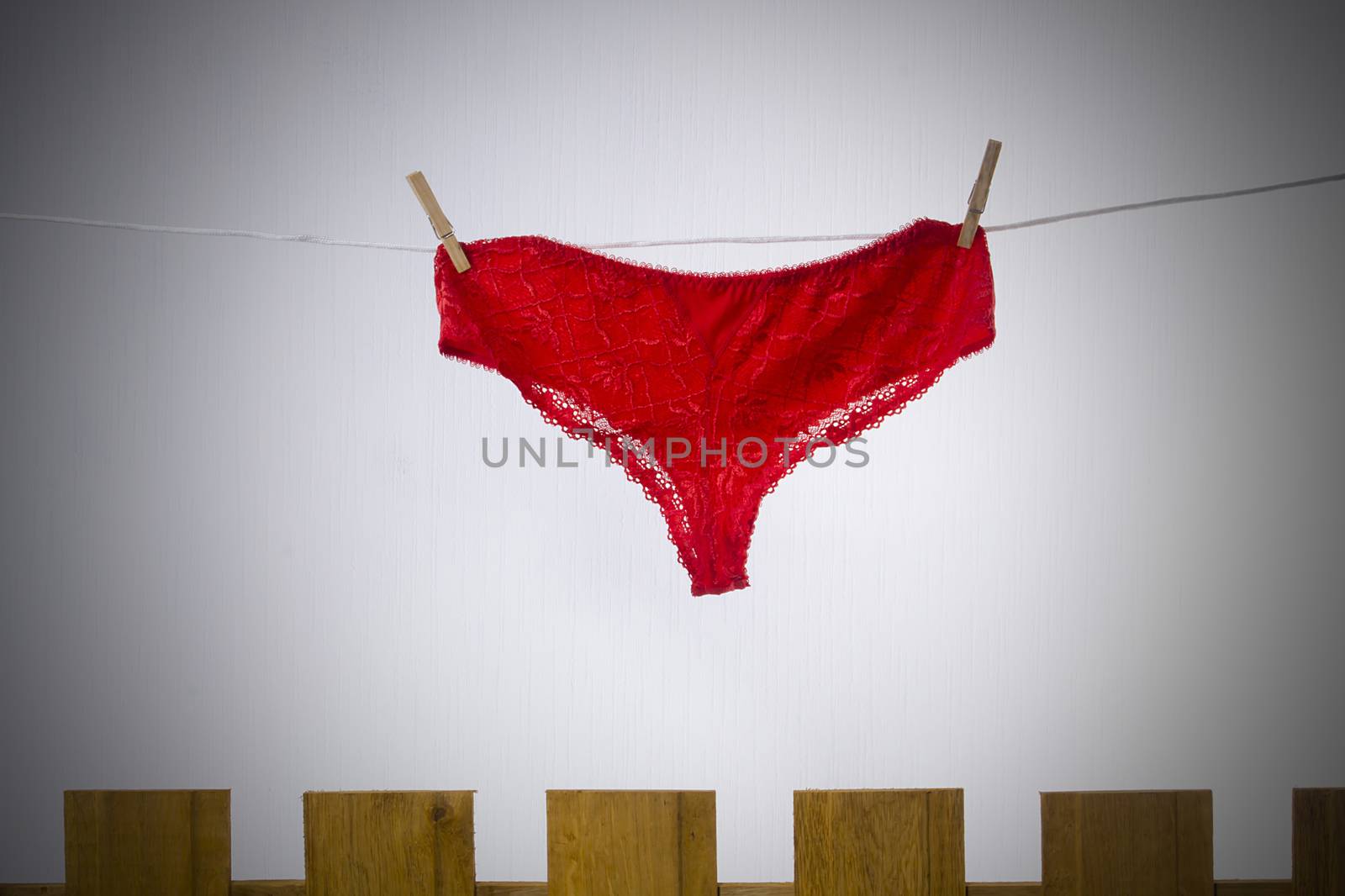 Female underwear dries on a rope behind a fence