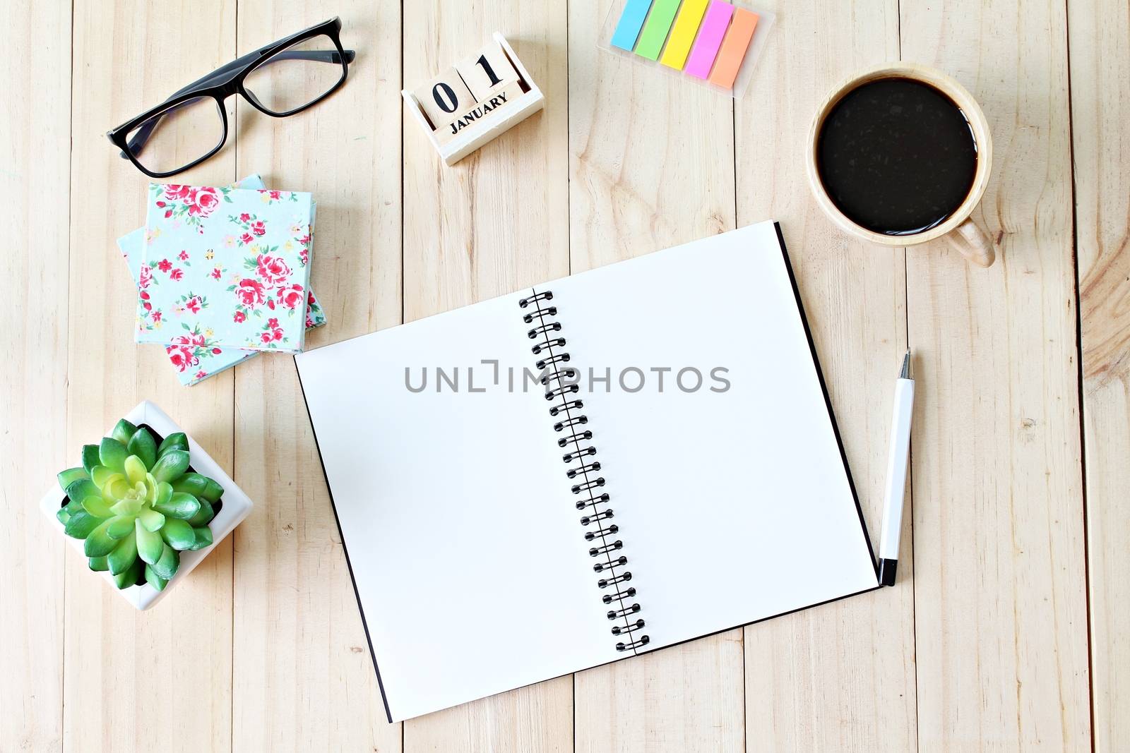 Still life, business office supplies or new year concept : Top view of working desk with blank notebook with pen, coffee cup, colorful note pad, cube calendar and eyeglasses on wooden background
