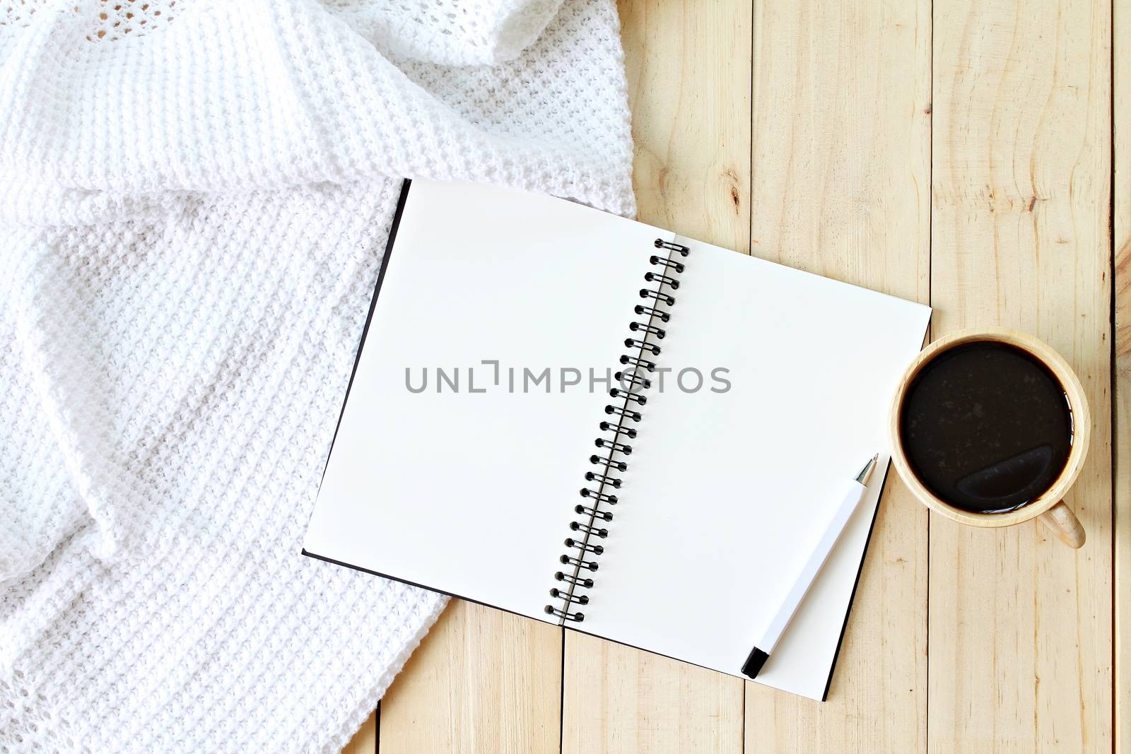 Business, Holiday or weekend concept : Flat lay of white knitted blanket, cup of coffee and blank notebook paper on wooden background