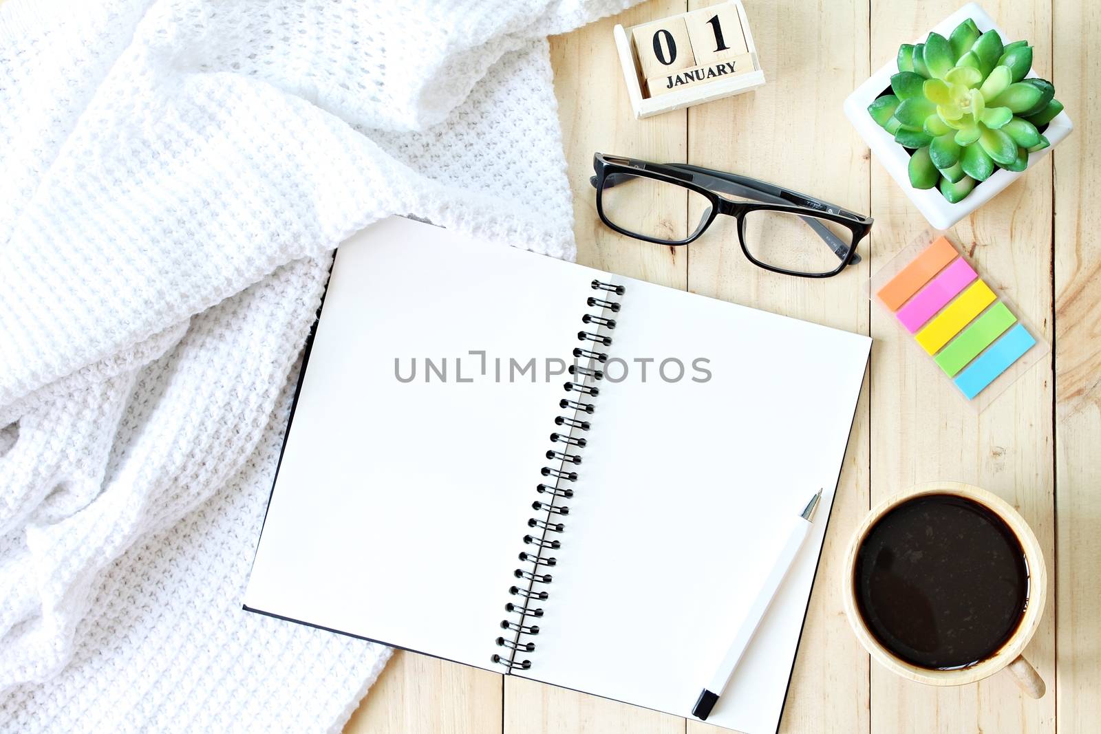 Business, weekend, holiday or new year planning concept : Flat lay or top view of  white knitted blanket, open blank notebook paper, coffee cup and new year cube calendar on wooden background