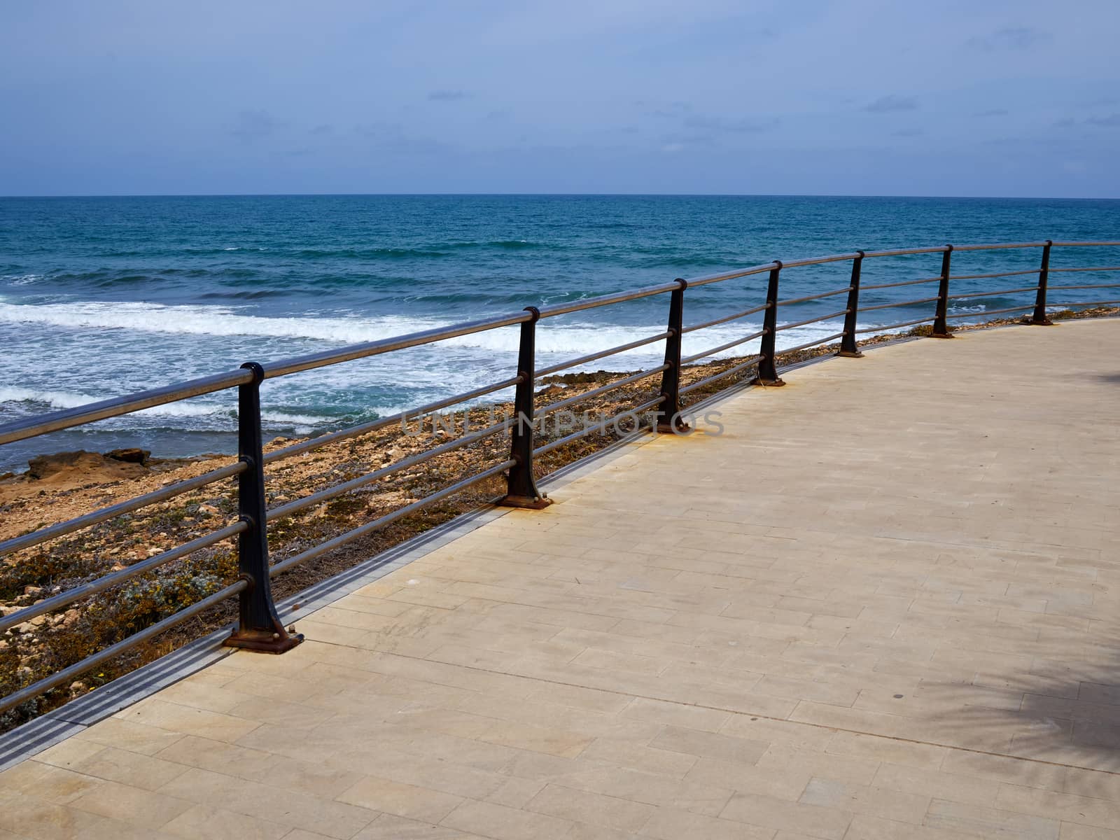 Beautiful beach seaside promenade with metal railings summer vacation attraction Spain