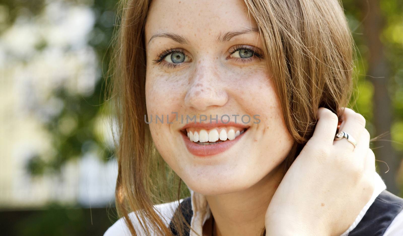 Portrait of young beautiful happy girl with freckles on her face