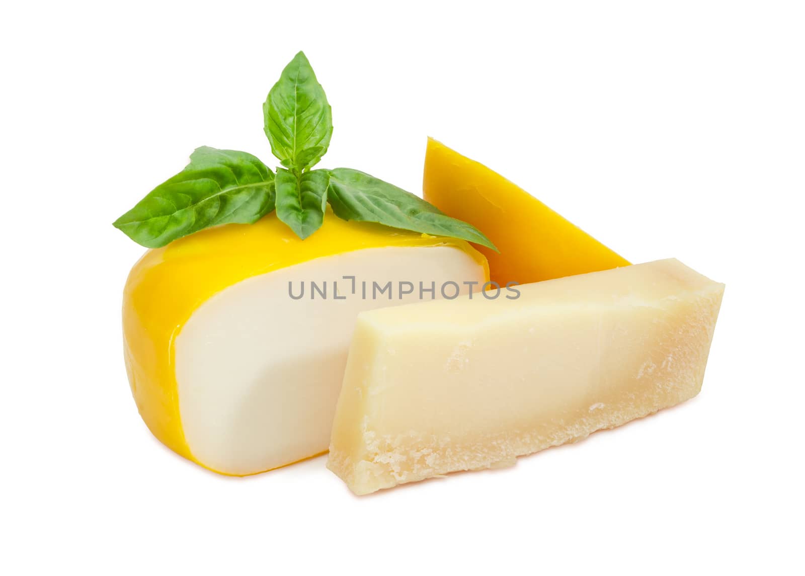 Piece of the parmesan cheese and partly sliced small wheel of firm goat cheese with twig of green basil on a white background
