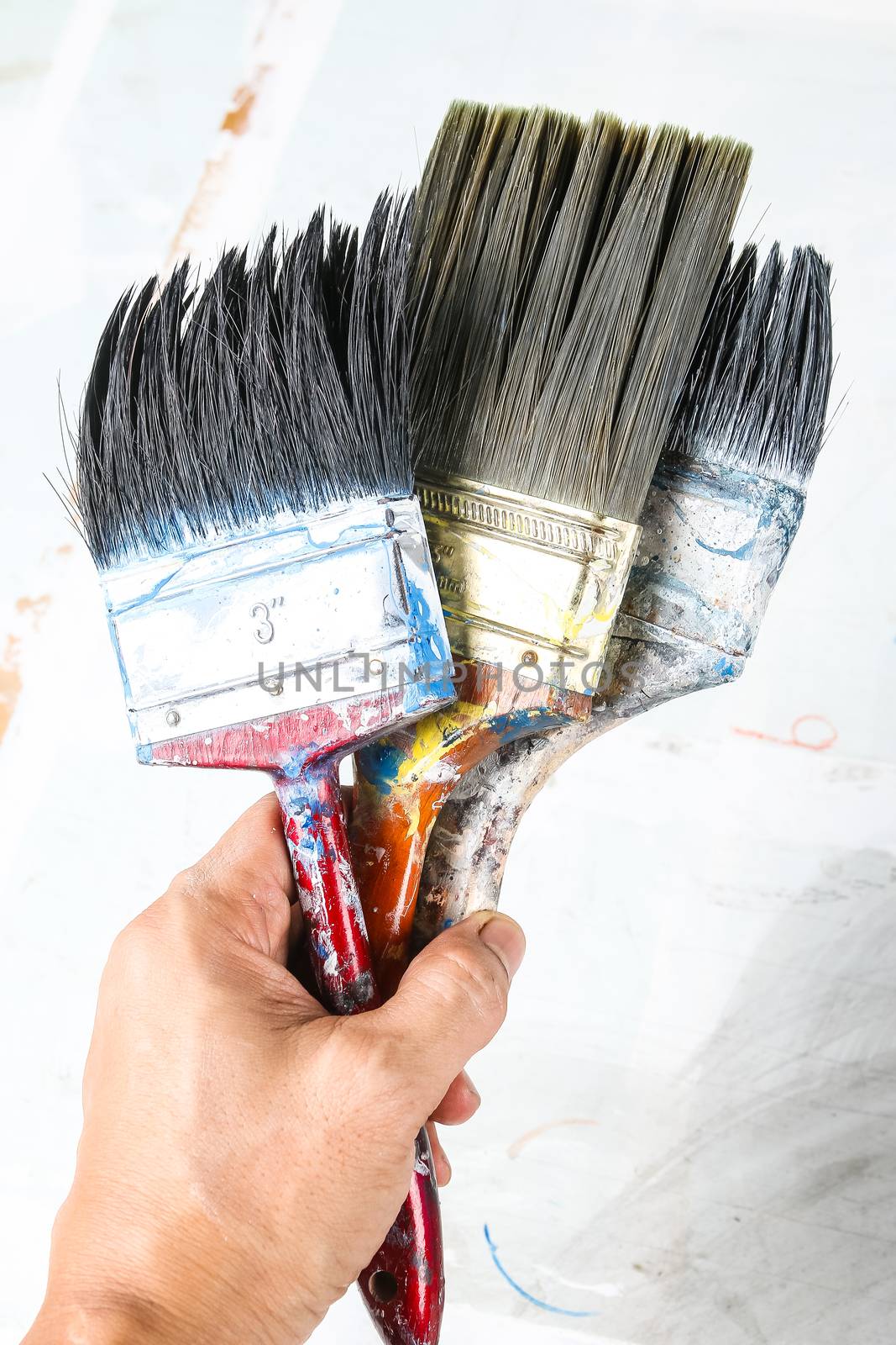 Close up of old paint brushes in hand, grunge and rusty texture background