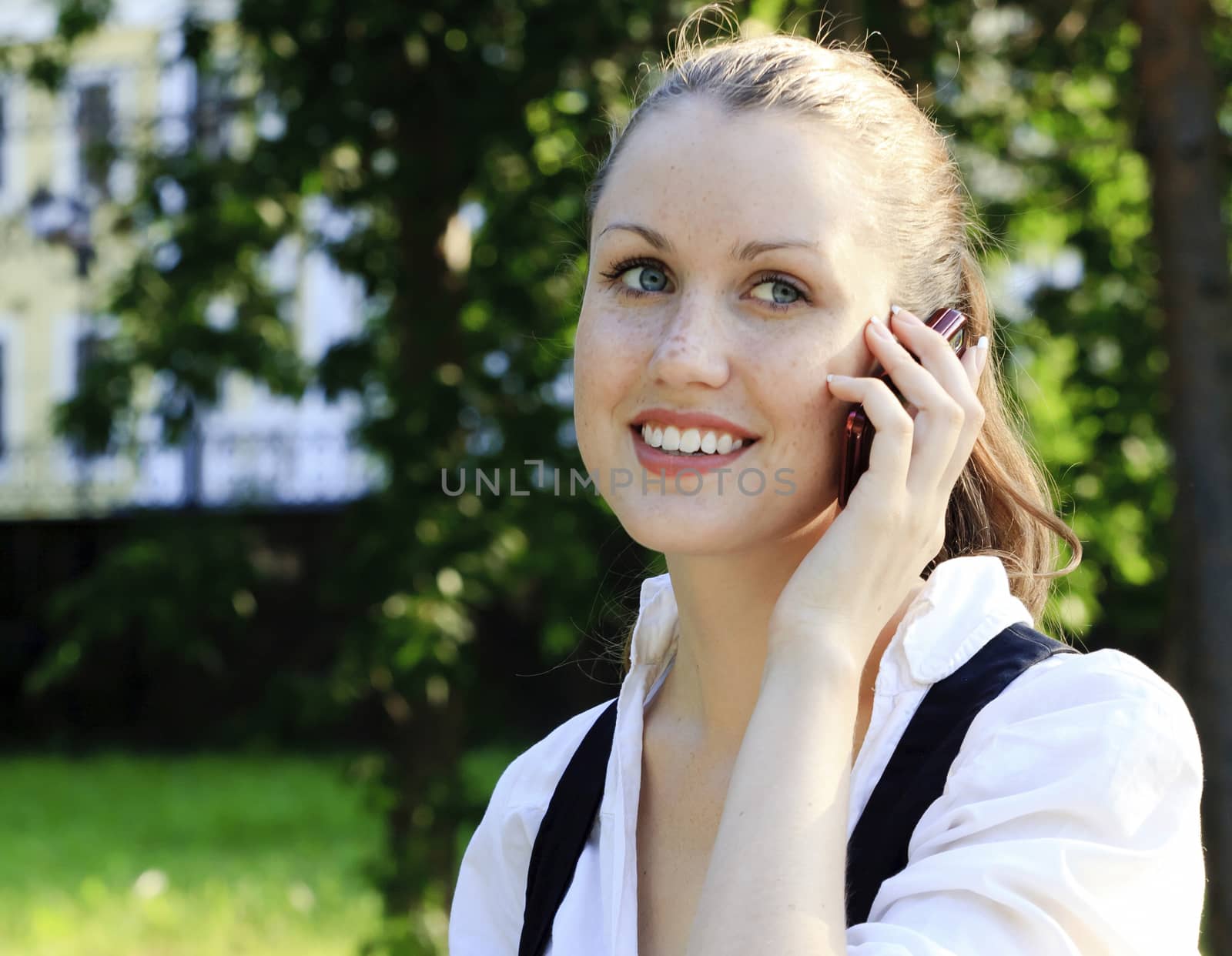 Closeup shot of young smiling woman speaks by a mobile phone by Nobilior