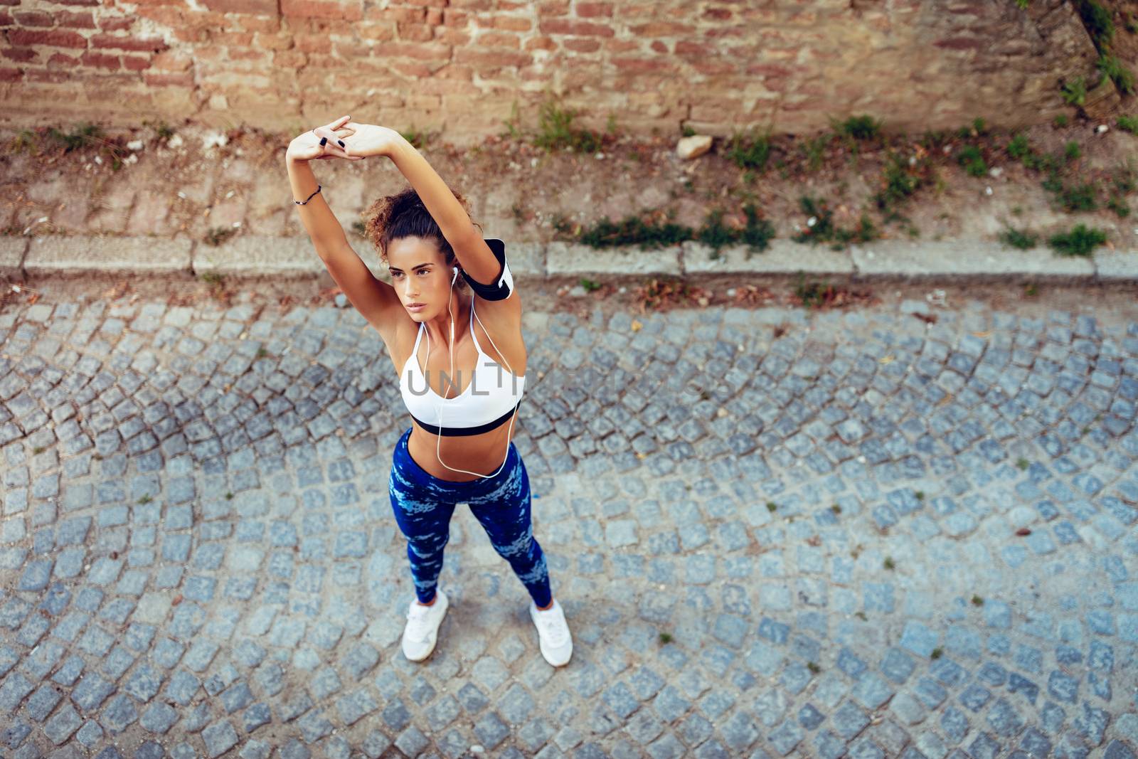Young fitness woman with headphones doing stretching exercise.