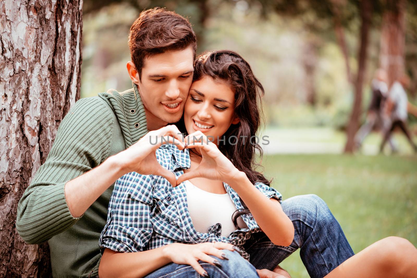 Beautiful lovely couple enjoying in park and with their hands making a heart shape.